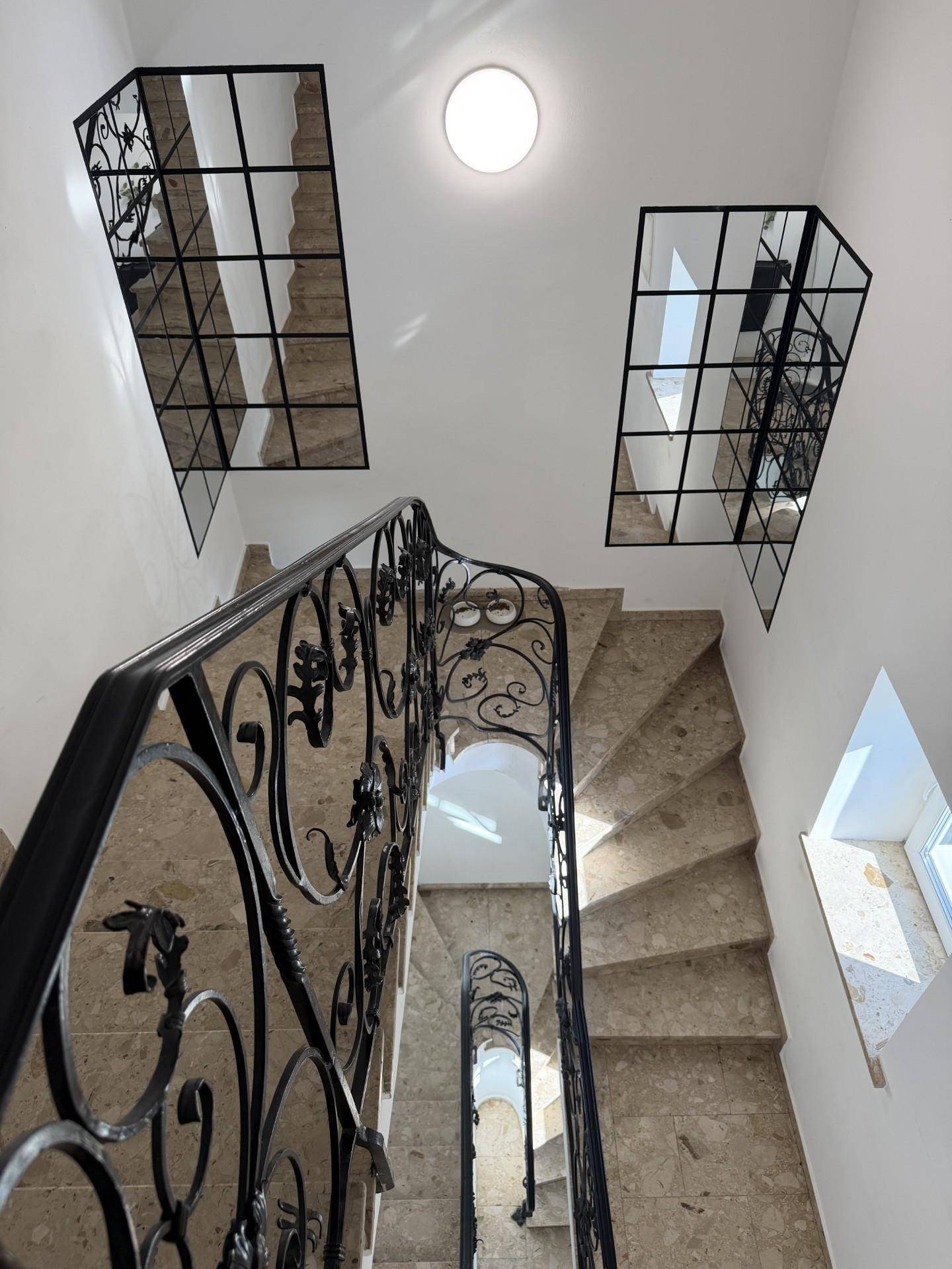 Elegantes Treppenhaus mit geschwungenem Geländer und Natursteinboden.