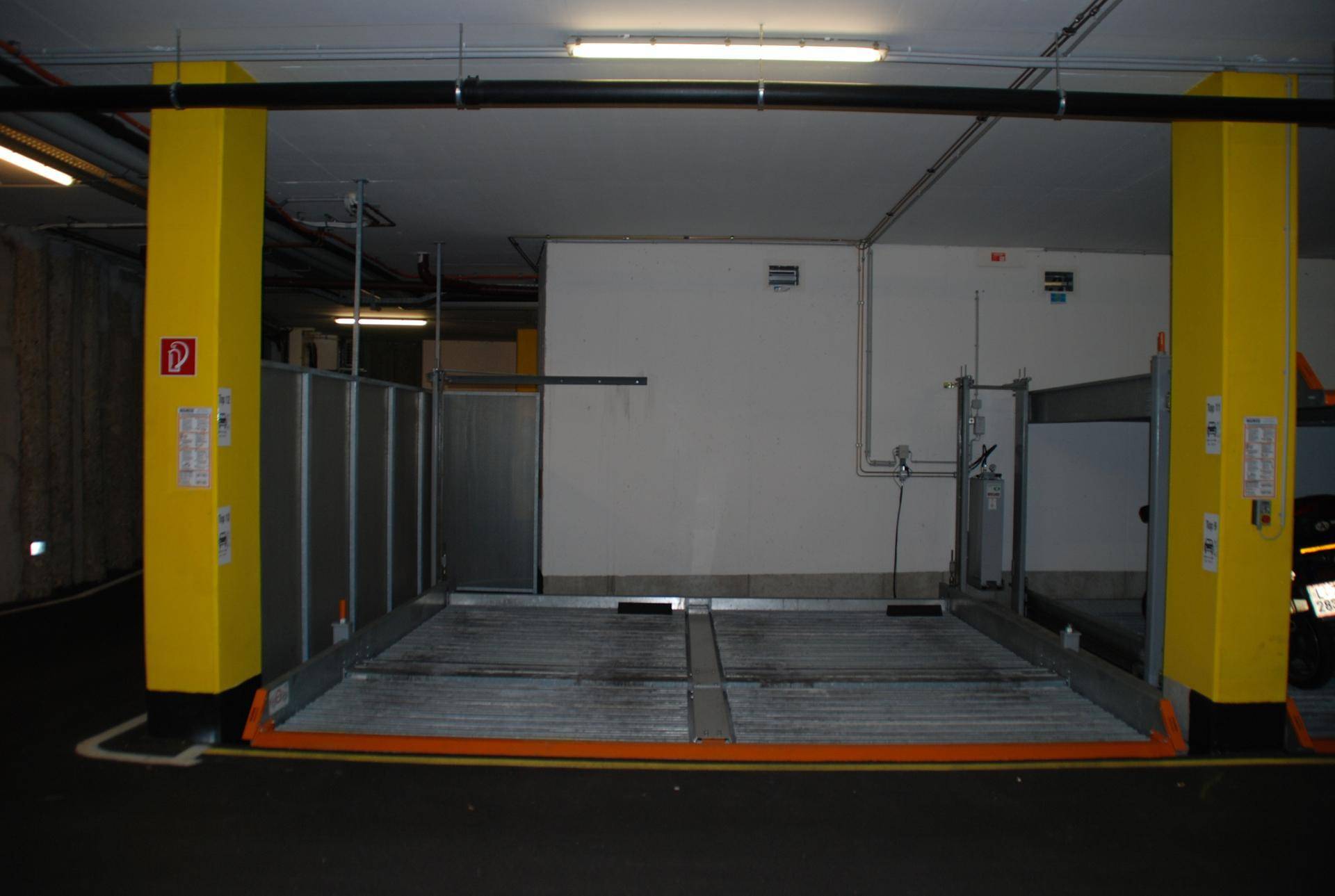 Geräumige Tiefgarage mit modernem Parksystem und hellen gelben Säulen für gute Orientierung.