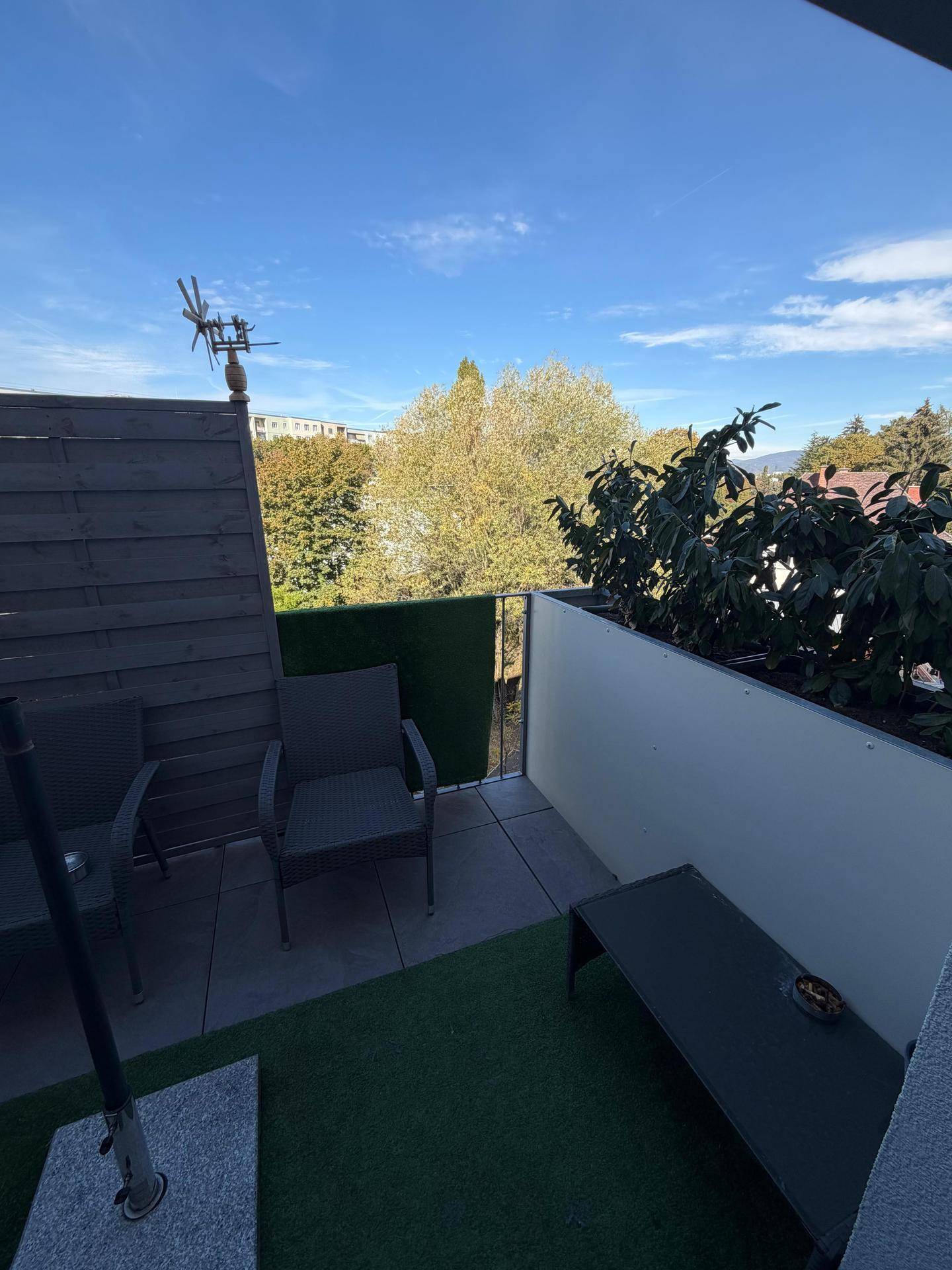 Sonniger Balkon mit Sitzgelegenheiten und einem angenehmen Blick ins Grüne.