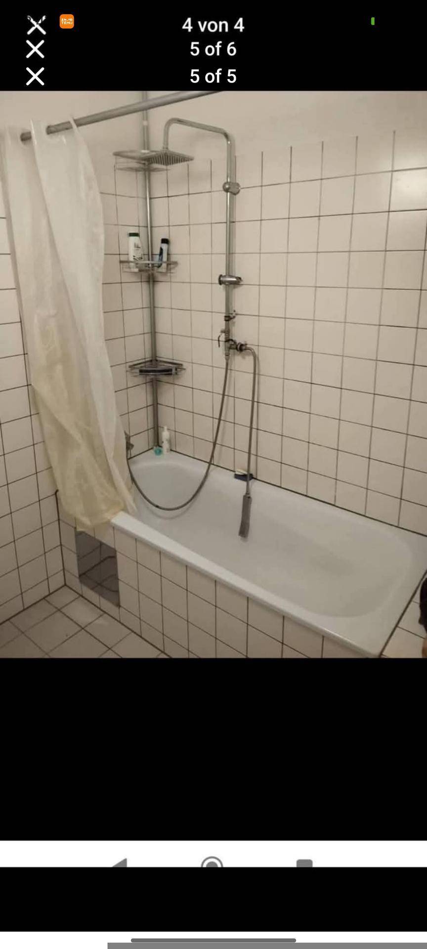 Badezimmer mit einer Badewanne, integrierter Dusche und weißen Wandfliesen.