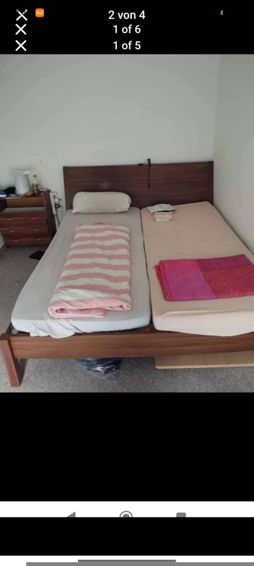 Schlafzimmer mit einem einfachen Holzbettrahmen und zwei Matratzen, bereit zur Einrichtung.