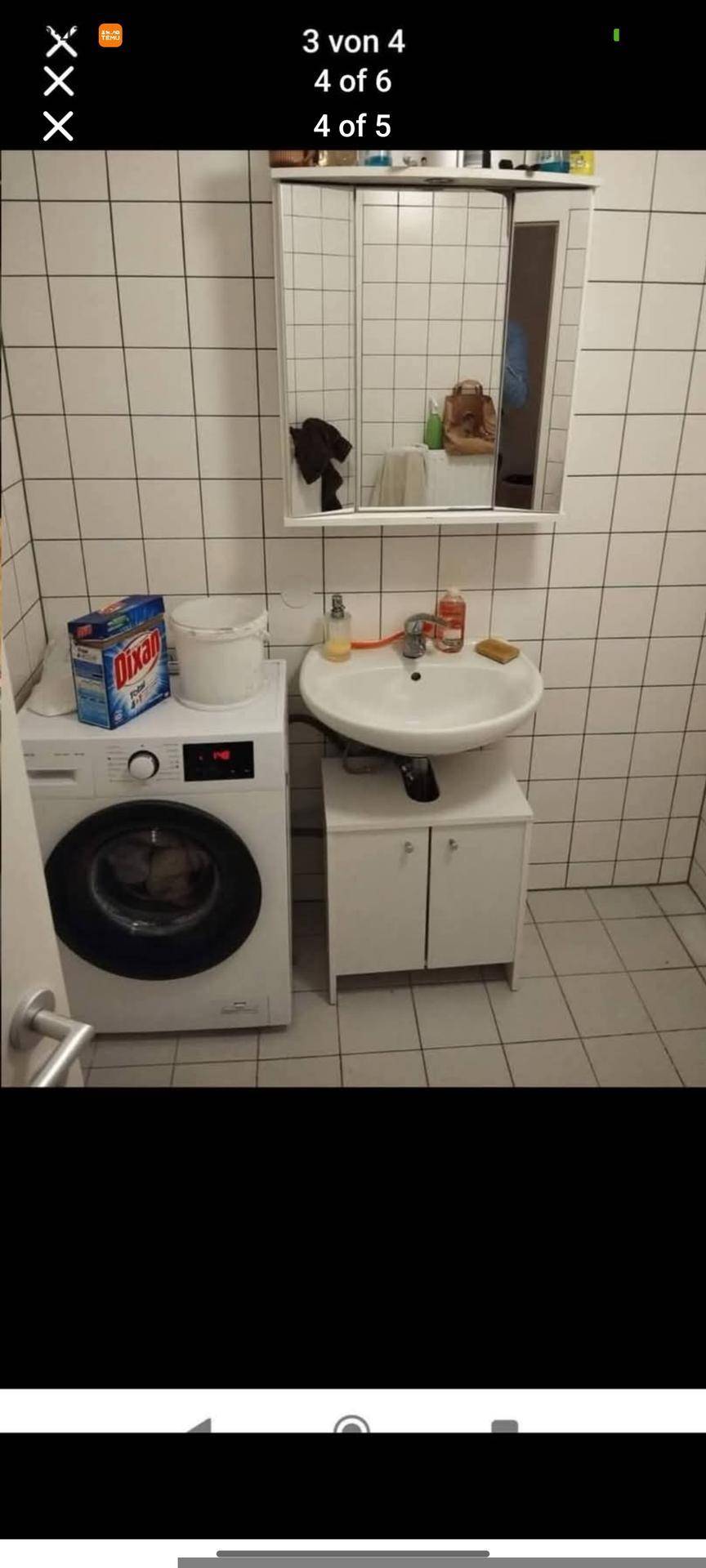 Helles Badezimmer mit weißen Fliesen, Waschbeckenunterschrank, Spiegelschrank und einer Waschmaschine.