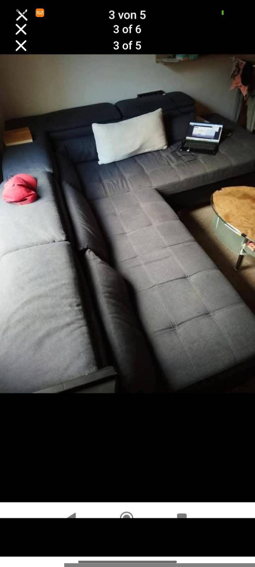 Gemütliches Wohnzimmer mit einem großen grauen Ecksofa und einem kleinen runden Beistelltisch.