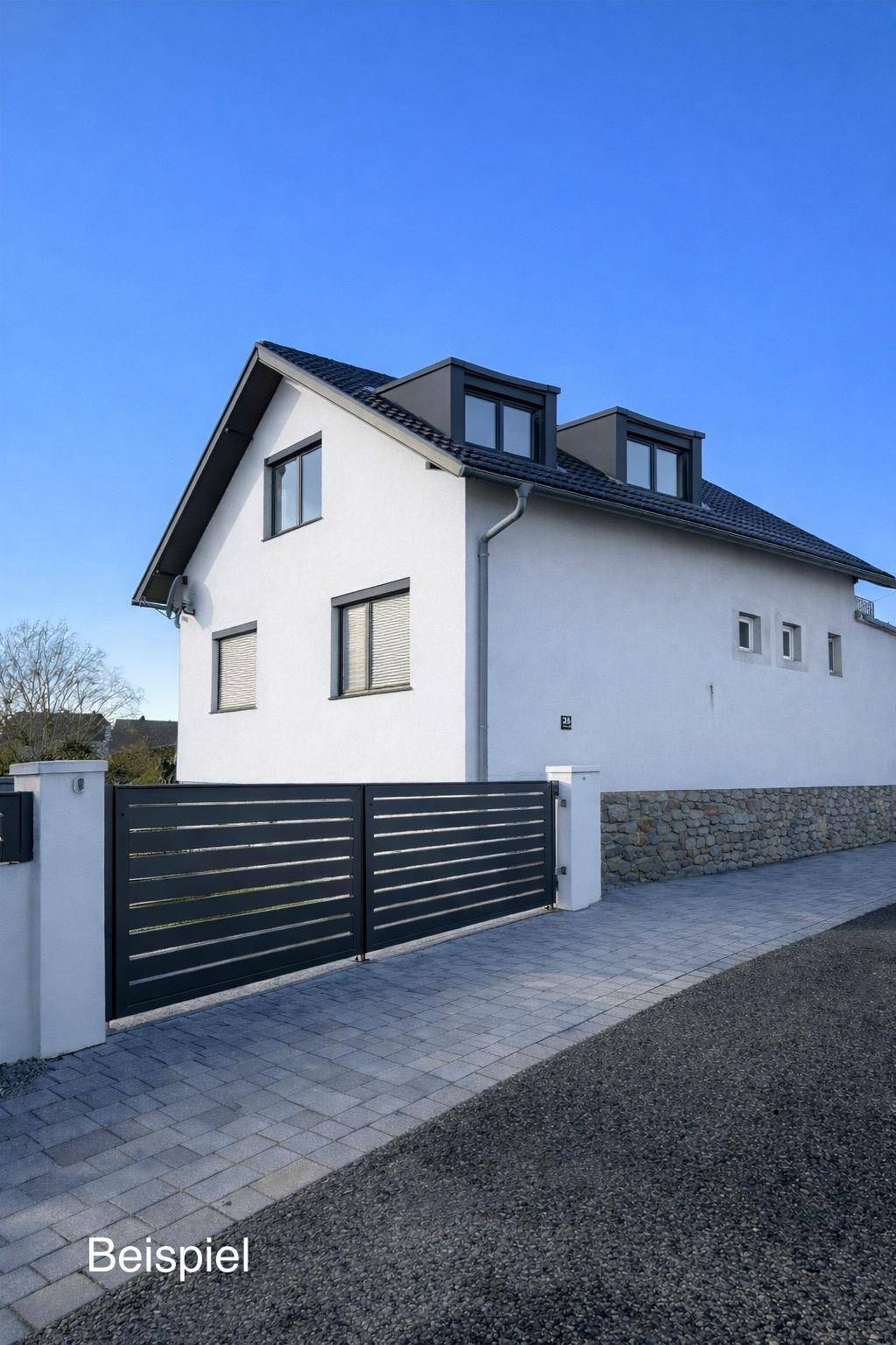 Modernisiertes Einfamilienhaus mit dunklem Satteldach, Gauben und einem eleganten schwarzen Eingangstor.