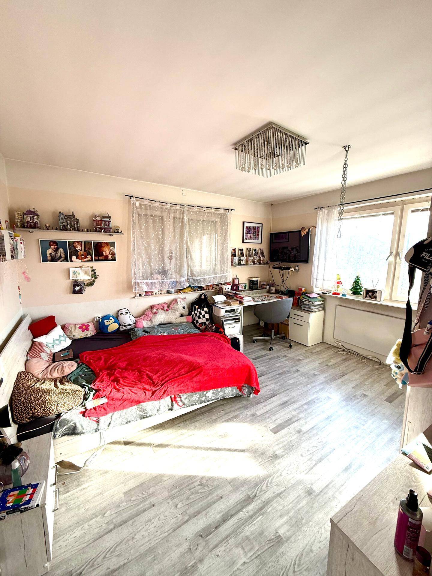 Kinderzimmer mit Bett, Schreibtisch und Laminatboden, hell und funktional eingerichtet.