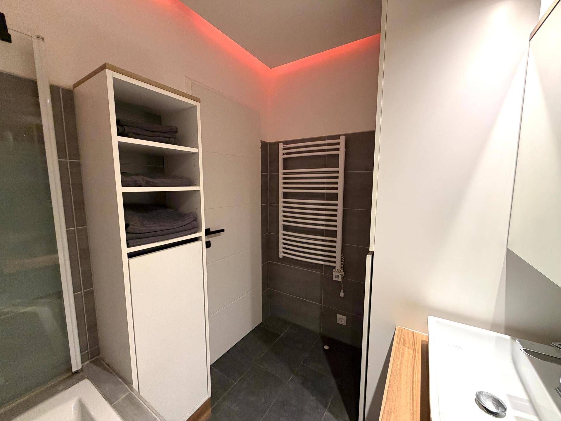 Modernes Badezimmer mit beheiztem Handtuchhalter und praktischem Stauraum.