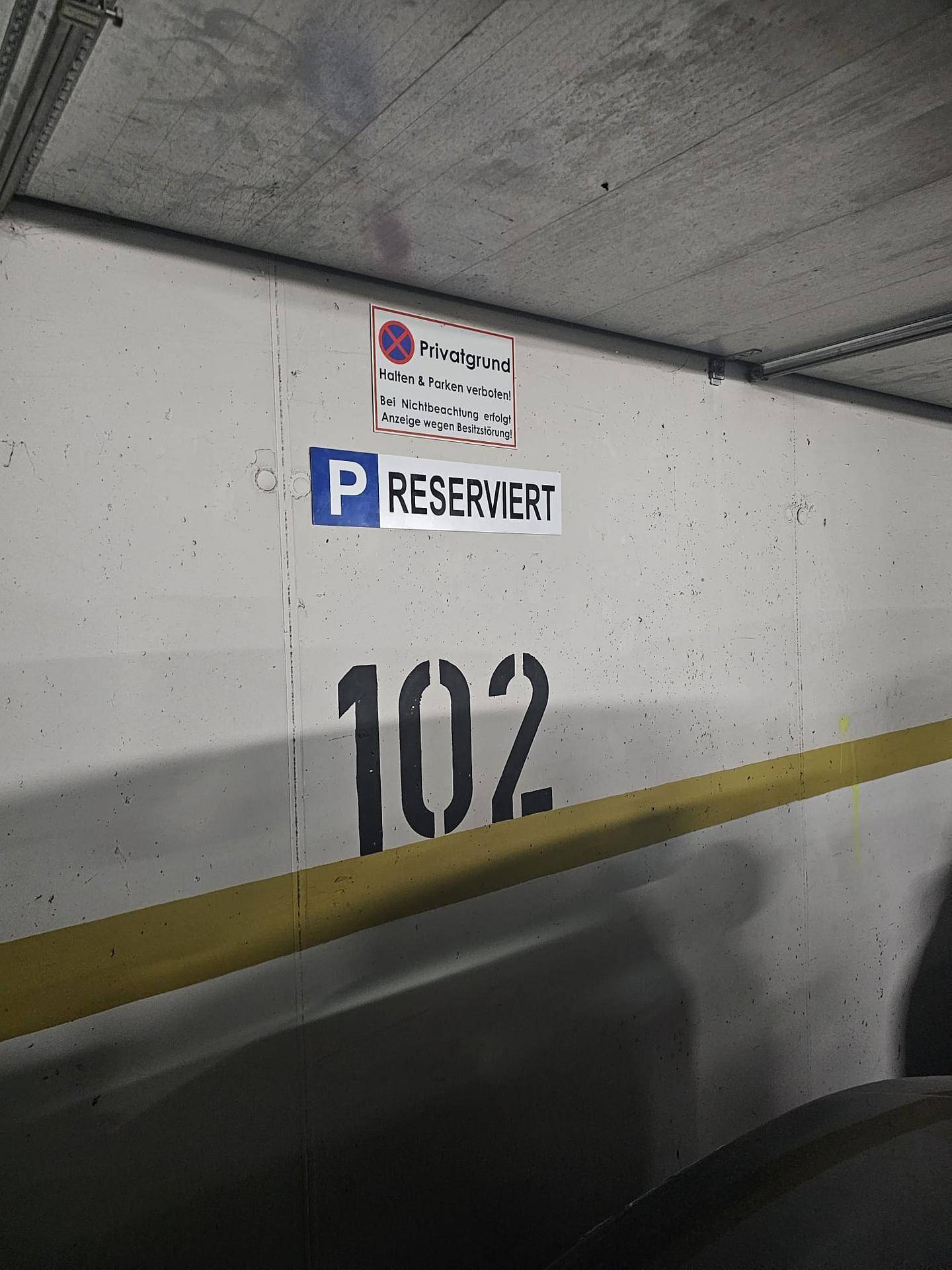 Nahaufnahme eines reservierten Parkplatzes Nummer 102 in einer Tiefgarage.