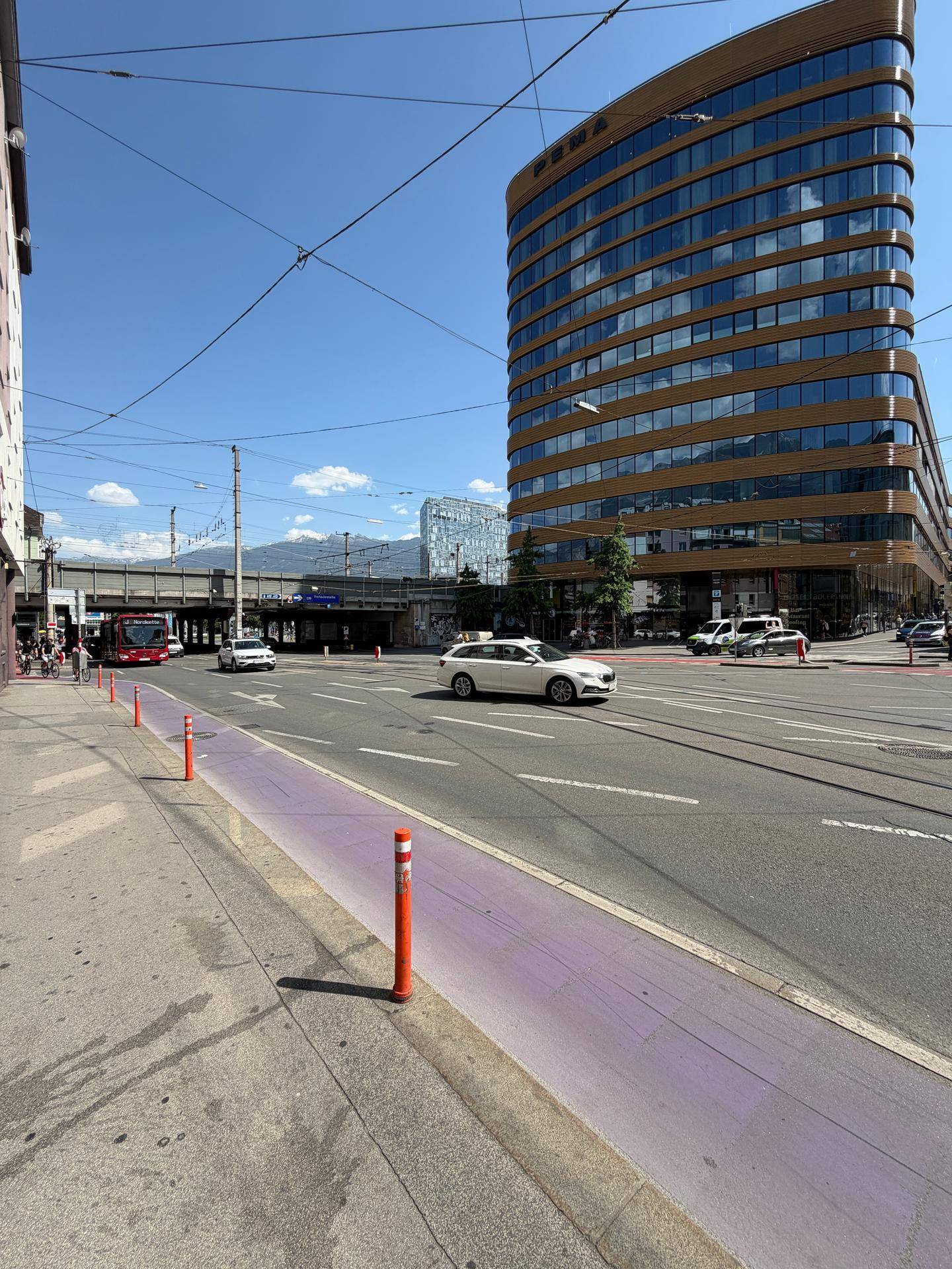 Moderne Architektur eines Bürogebäudes an einer belebten Straße mit Bergblick im Hintergrund.