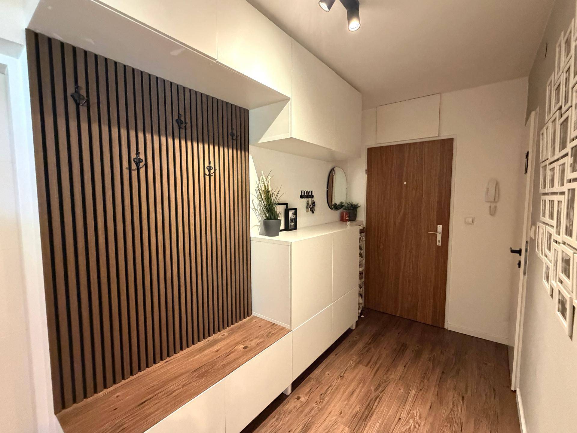 Moderner Eingangsbereich mit Holzlamellenwand, Sitzbank und Schuhschrank.