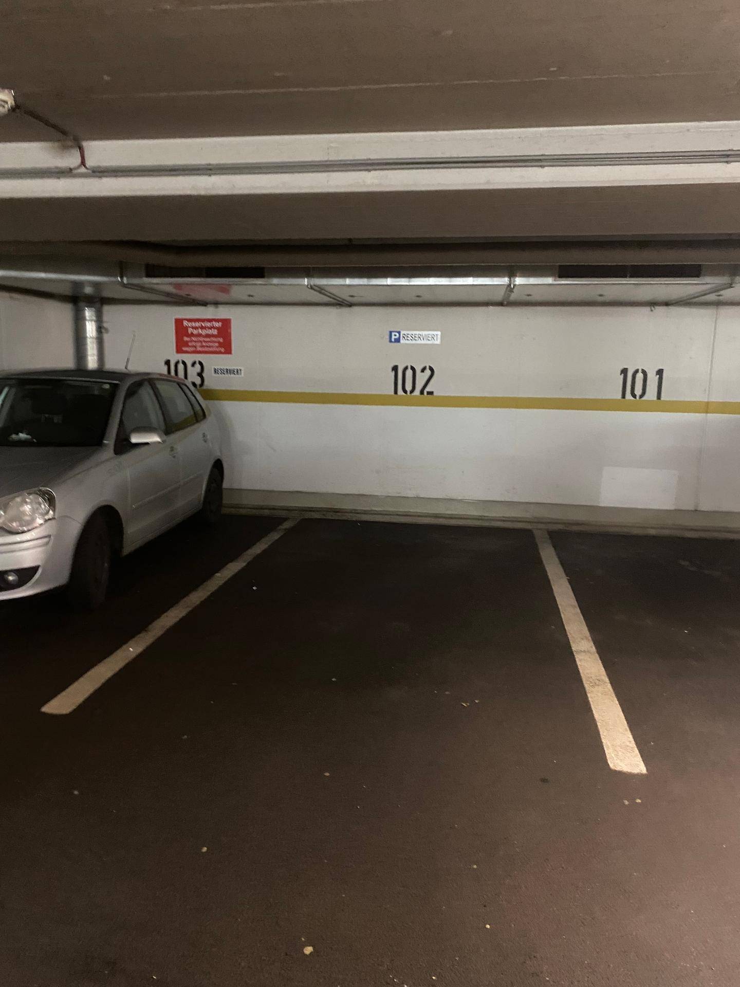 Reservierter Stellplatz in einer Tiefgarage mit Betonwänden und Decken.