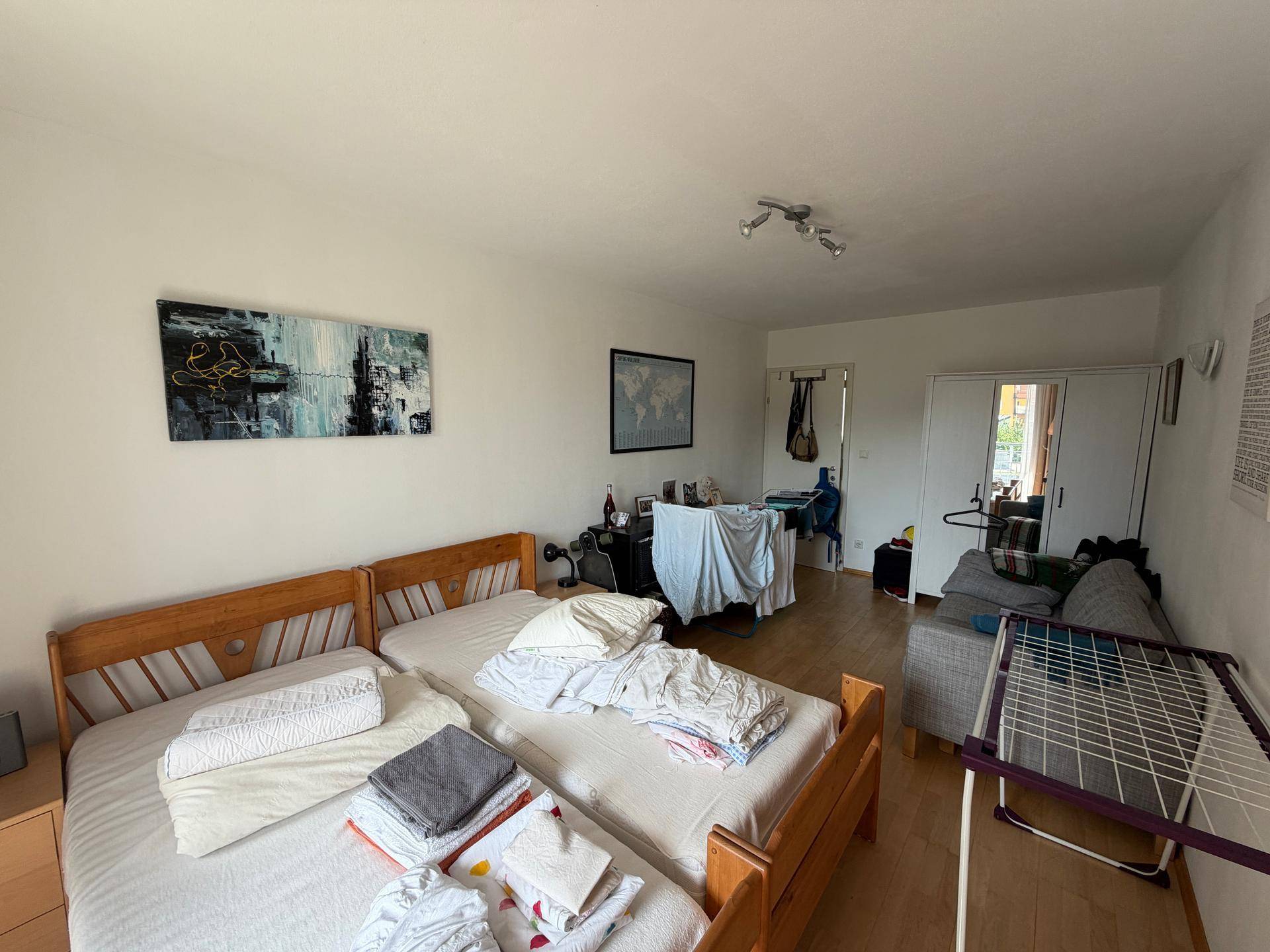 Schlafzimmer mit zwei Einzelbetten, einem Schreibtisch und einem Spiegel, hell und funktional eingerichtet.