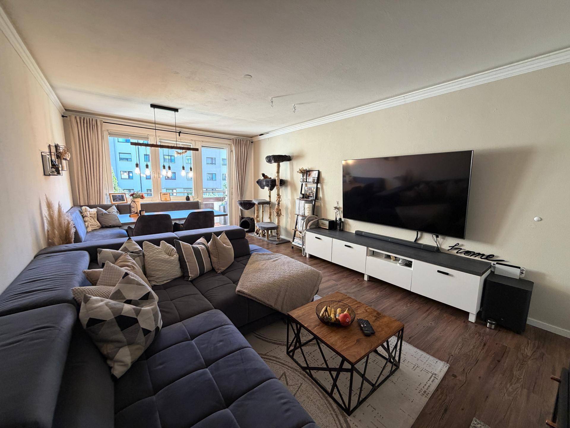 Geräumiger Wohn-Essbereich mit großem Sofa, Fernseher und Essbereich.