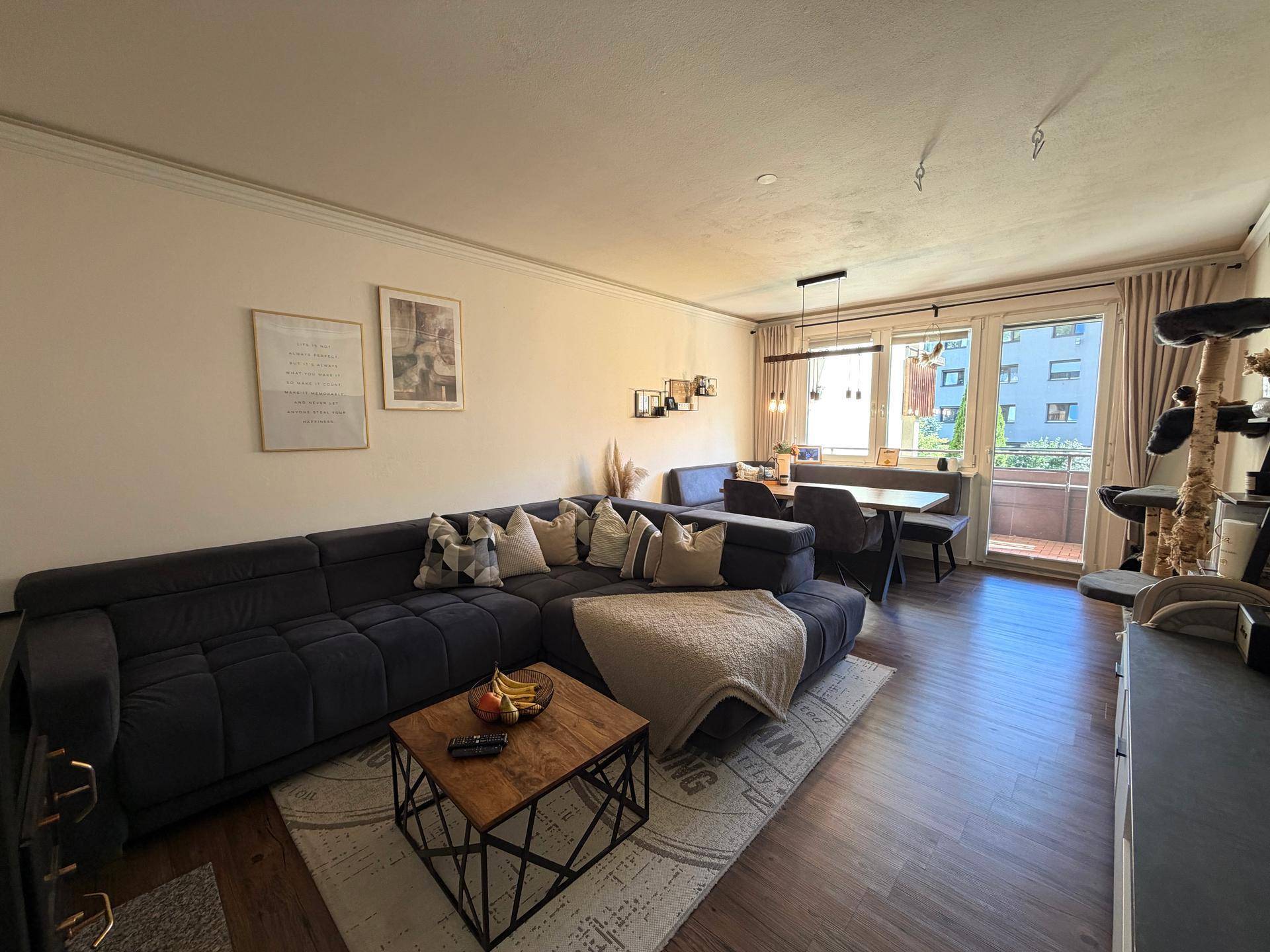 Gemütlicher Wohn-Essbereich mit großem Sofa, Esstisch und Zugang zum Balkon.
