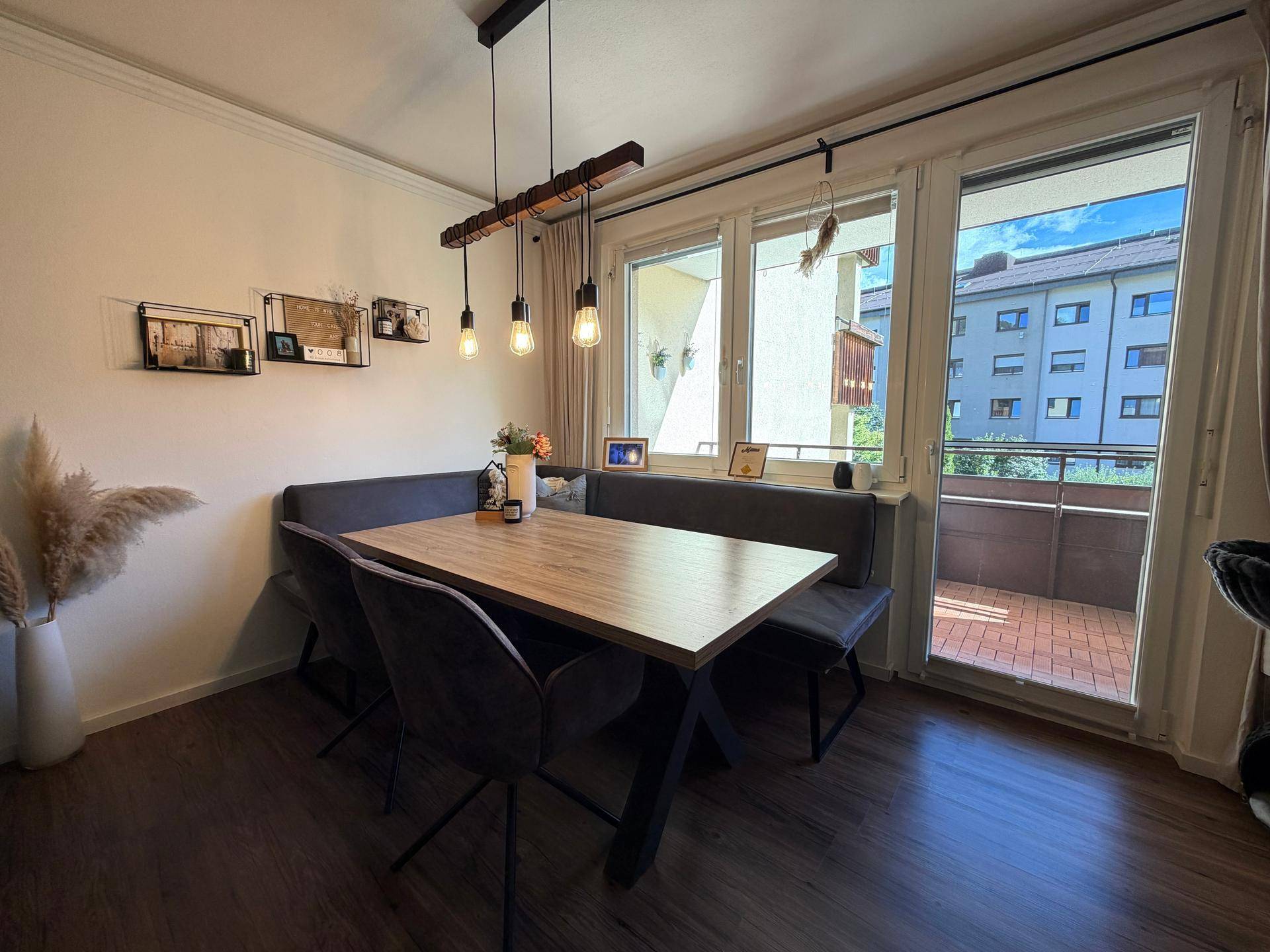 Heller Essbereich mit Holztisch, Sitzbank und Zugang zum Balkon.