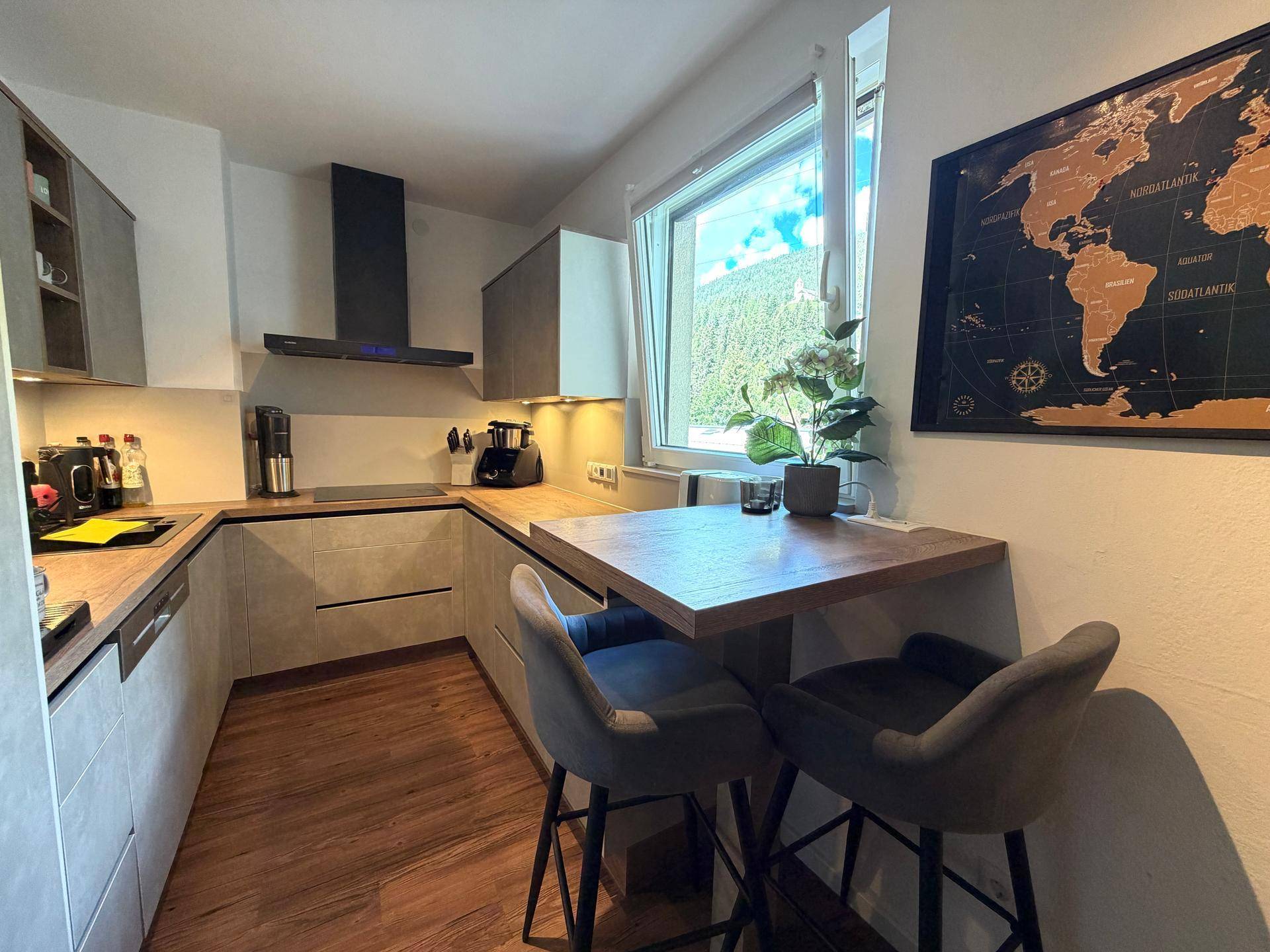 Moderne Küche mit Frühstücksbar, Fenster und Weltkarte an der Wand.