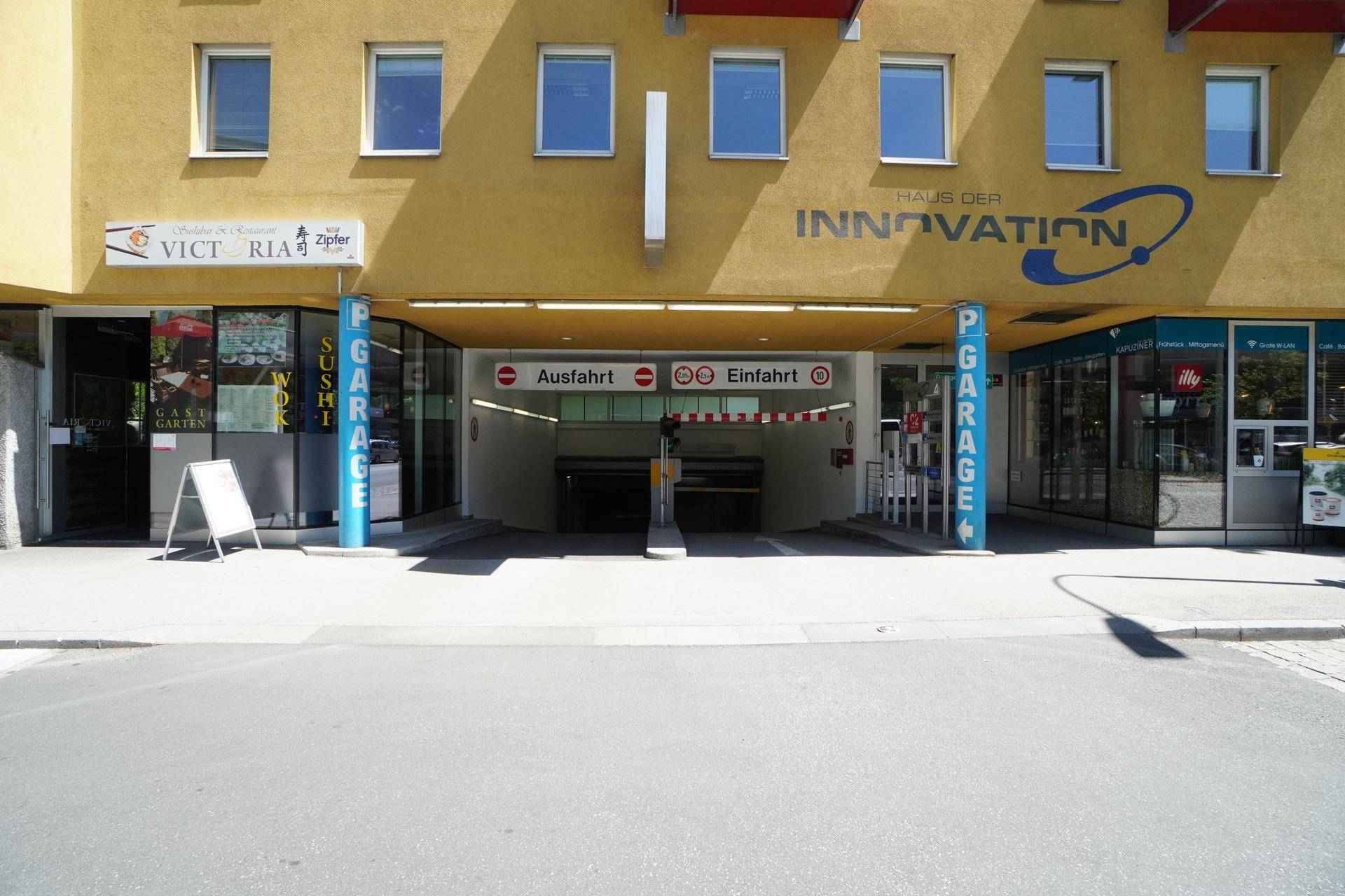 Einfahrt zu einer Tiefgarage unter einem Gebäude mit gelber Fassade.