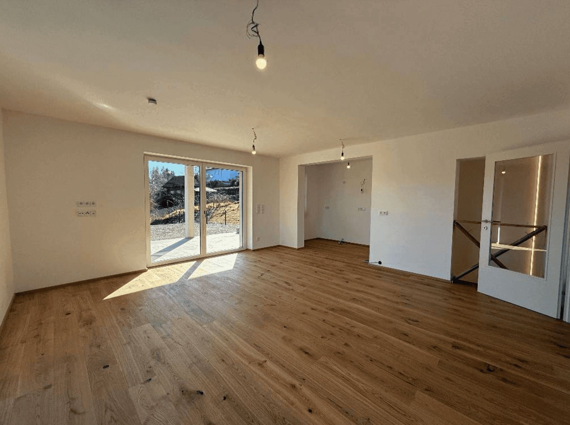 Geräumiges Wohnzimmer mit hellem Holzboden und Schiebetür zum Außenbereich, ideal für offenes Wohnen.