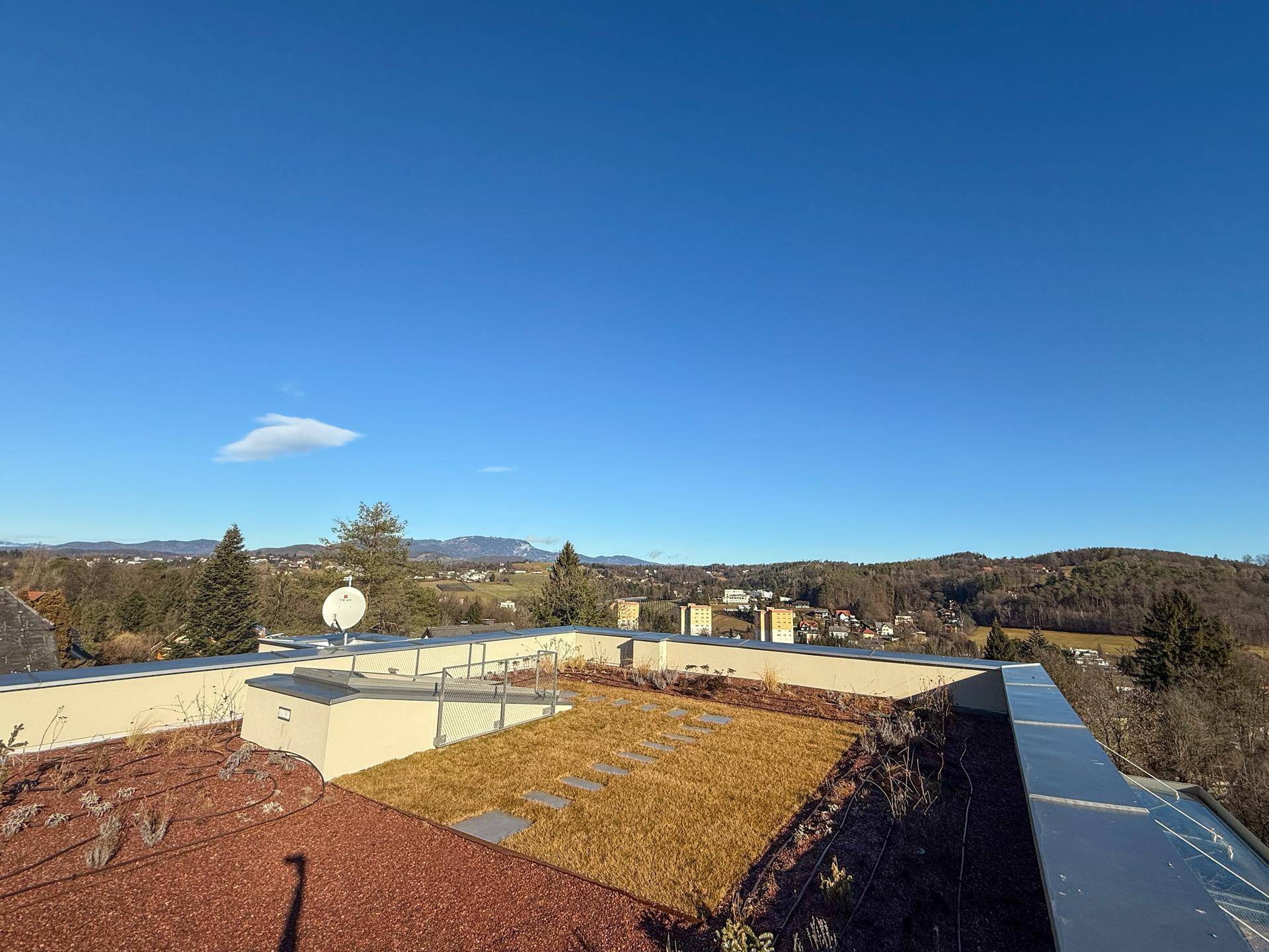 Attraktive Dachterrasse mit Grünflächen und Panoramablick auf die umliegende Landschaft.