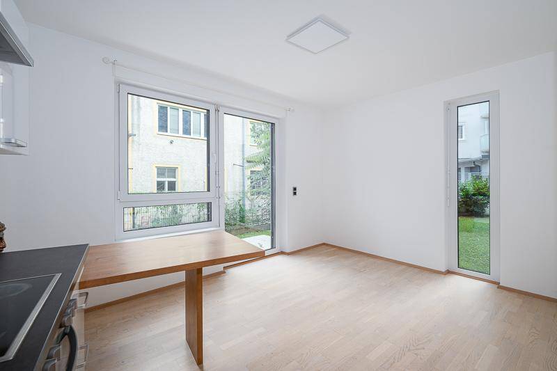Heller Essbereich mit Holztisch und großen Fenstern, die den Blick ins Grüne ermöglichen.