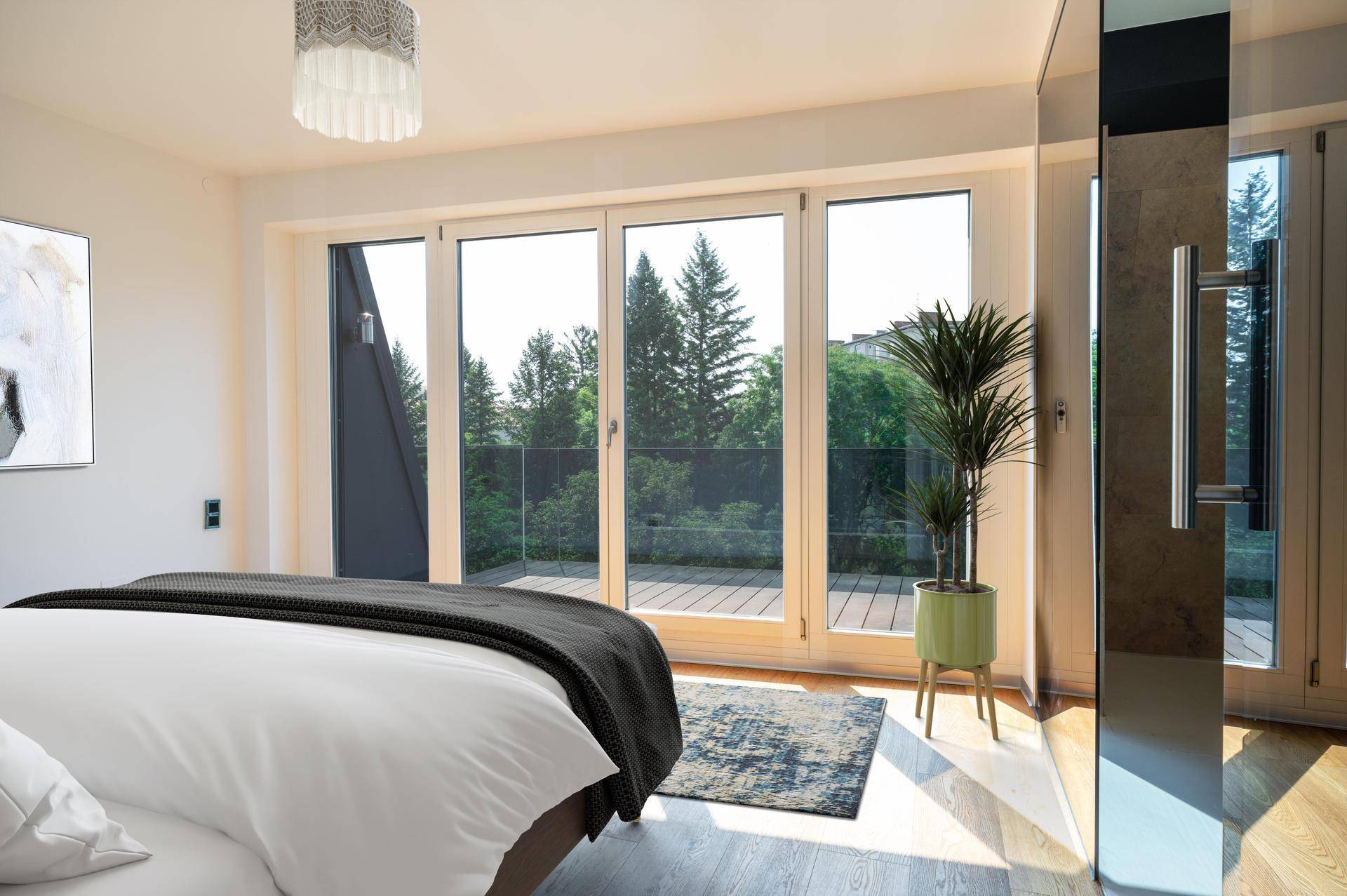 Helles Schlafzimmer mit Holzboden, großen Fenstern und direktem Zugang zu einer Terrasse.