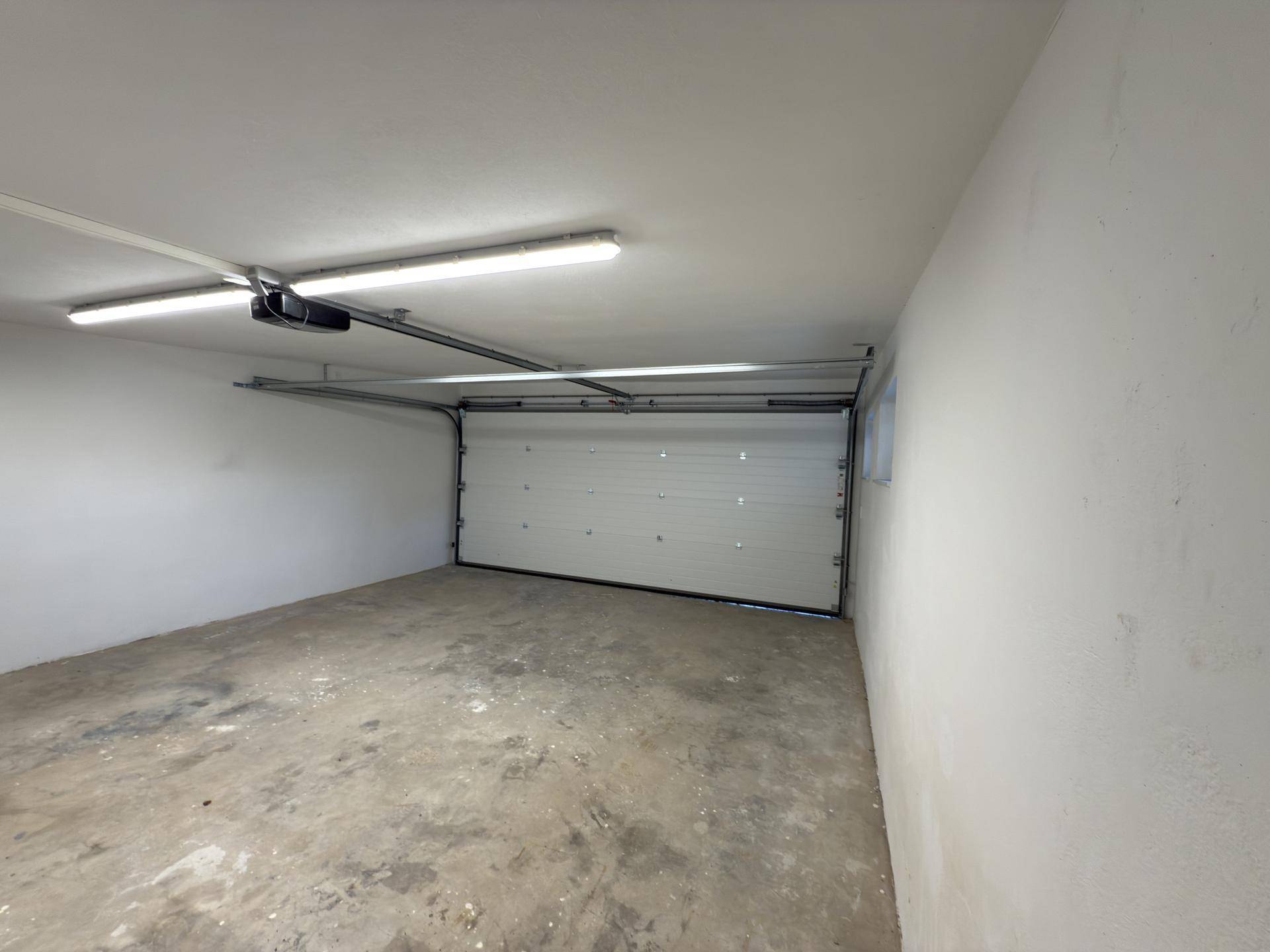 Innenansicht der Garage mit Betonboden und automatischem Garagentor.