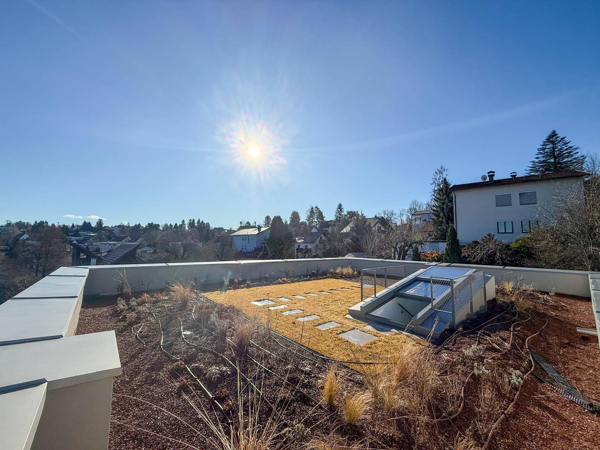 Begrünte Dachterrasse mit Sitzgelegenheiten und weitem Blick über die Umgebung.