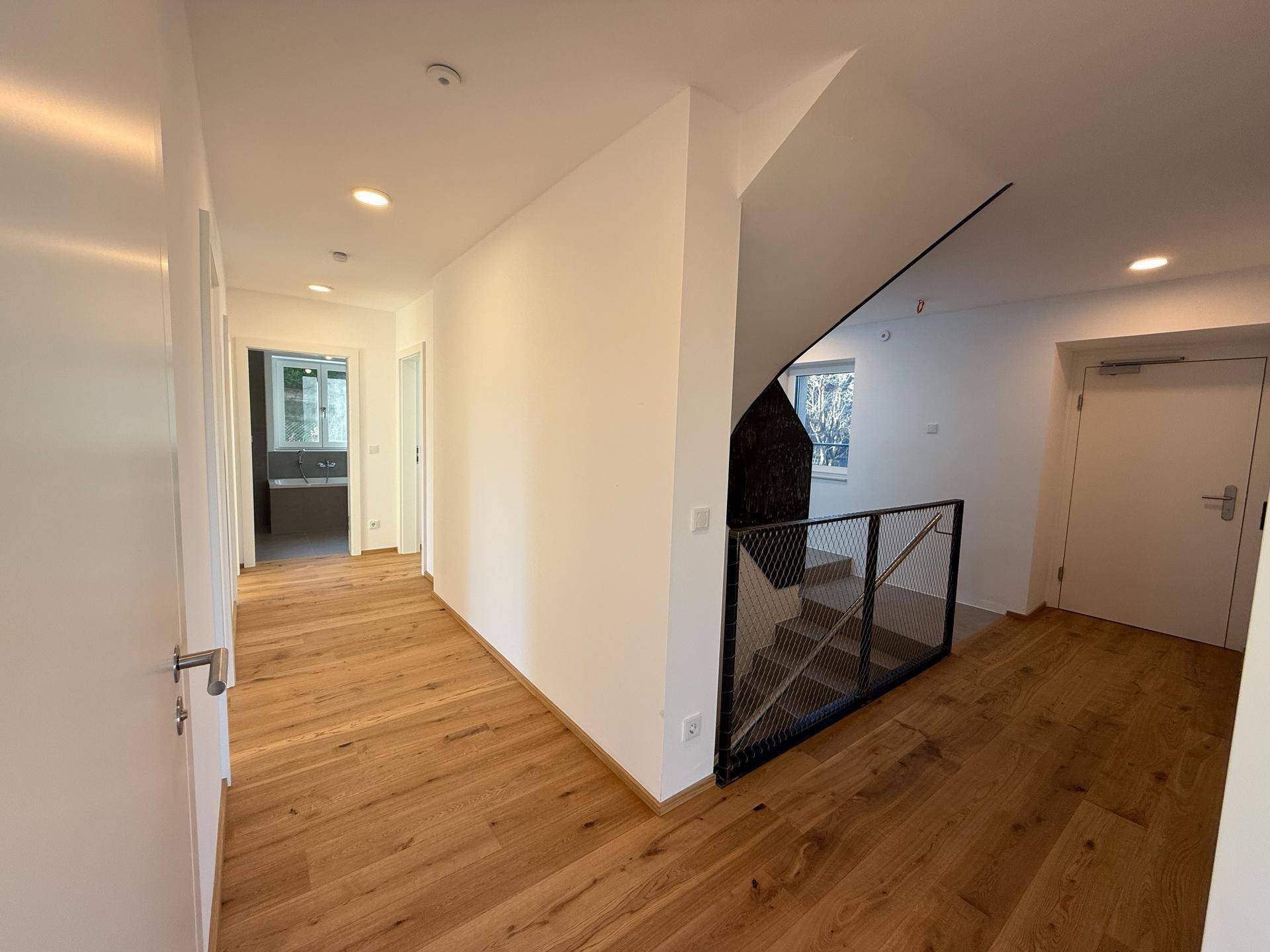 Heller Flur mit Holzboden und moderner Treppe, die die verschiedenen Ebenen verbindet.