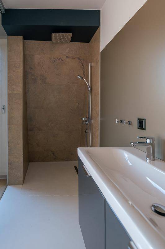 Modernes Badezimmer mit begehbarer Dusche, Regenbrause und eleganten Fliesen.