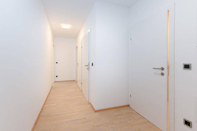Heller Flur mit hellem Holzparkett und mehreren weißen Türen, die zu den Zimmern führen.