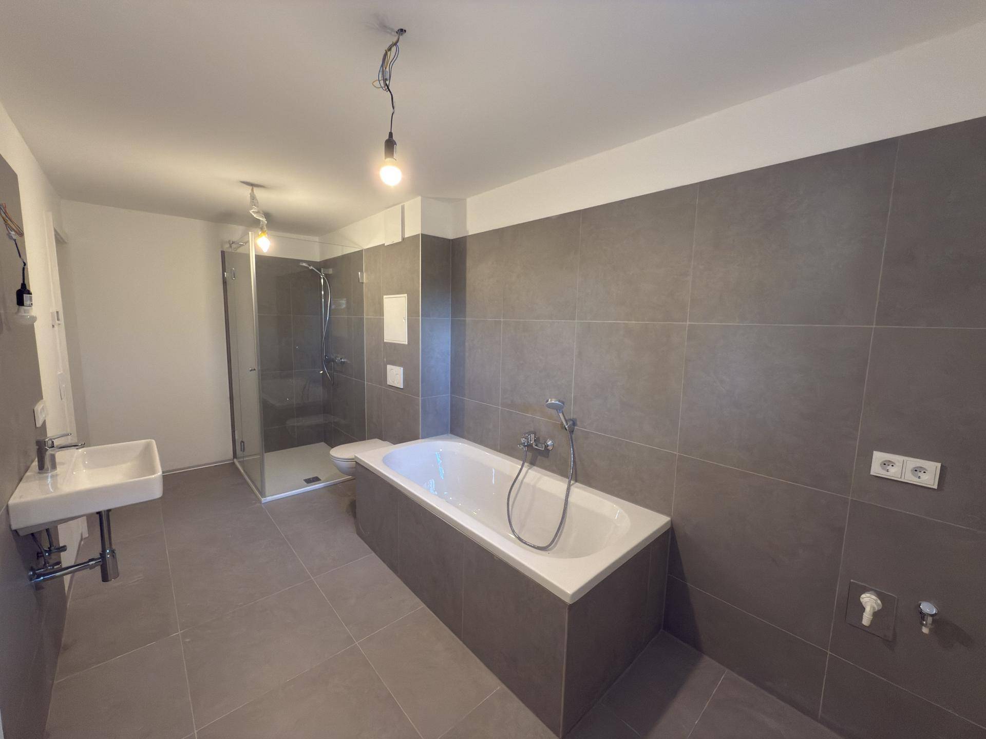 Modernes Badezimmer mit Badewanne, Duschkabine, Wand-WC und Einzelwaschbecken.