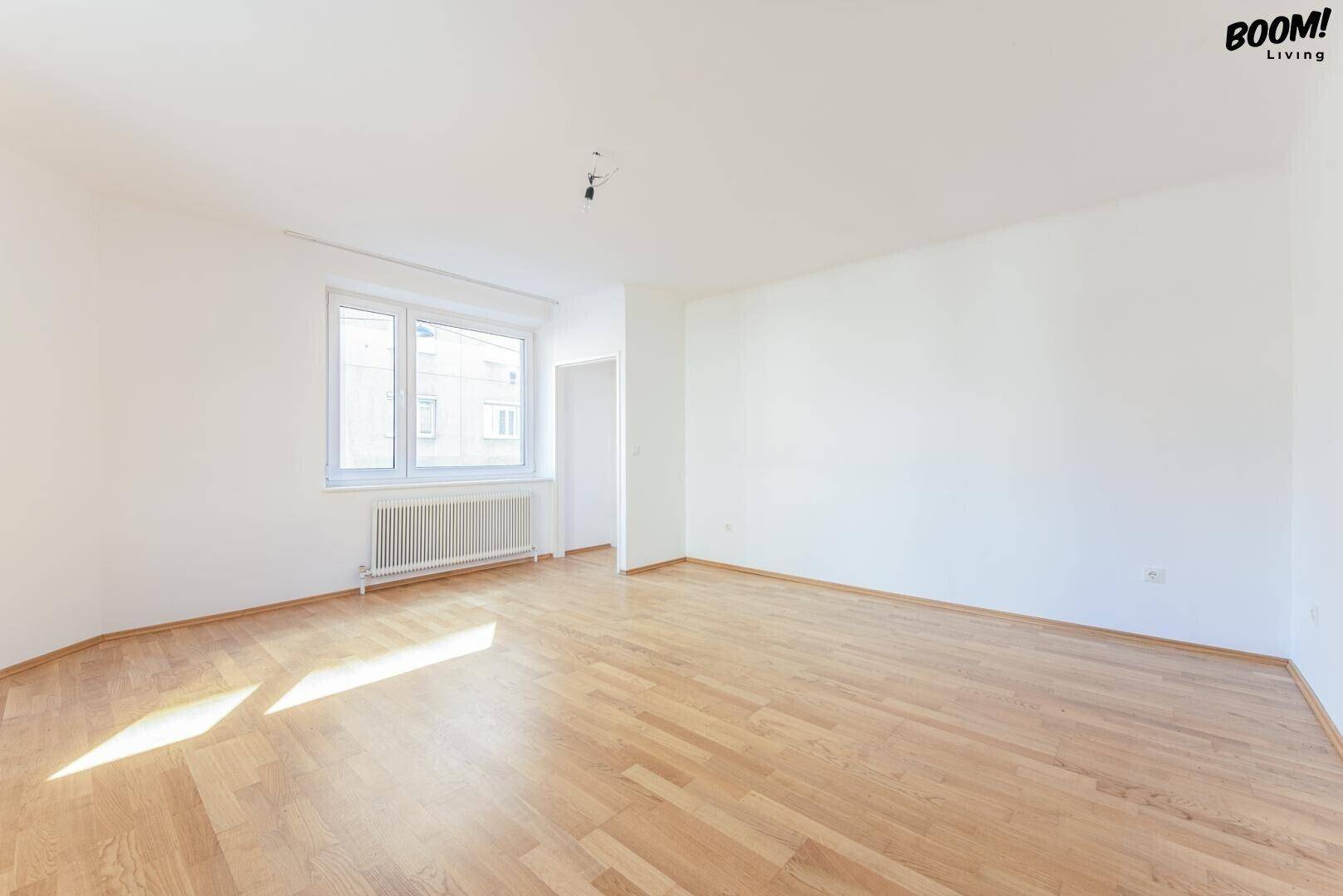Lichtdurchflutetes Zimmer mit Parkettboden und einem Fenster, ideal für Wohn- oder Schlafbereich.