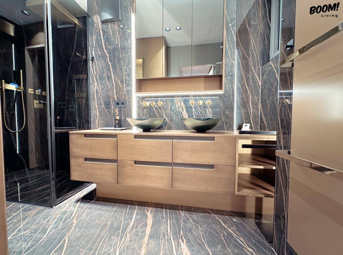 Luxuriöses Badezimmer mit dunklen Marmorfliesen, Doppelwaschbecken und begehbarer Dusche.