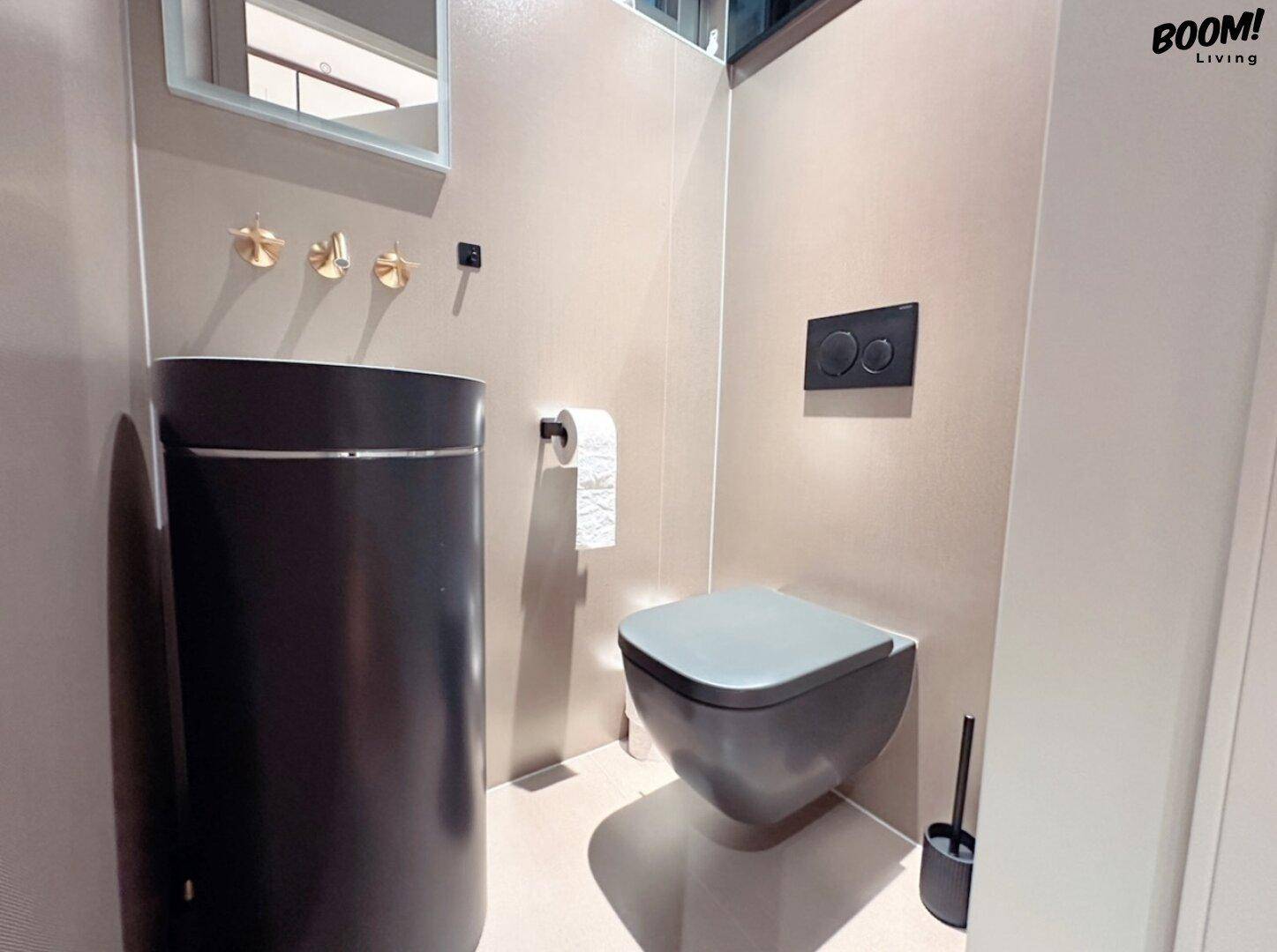 Modernes Gäste-WC mit schwarzer Toilette, zylindrischem Waschbecken und Wandarmaturen.