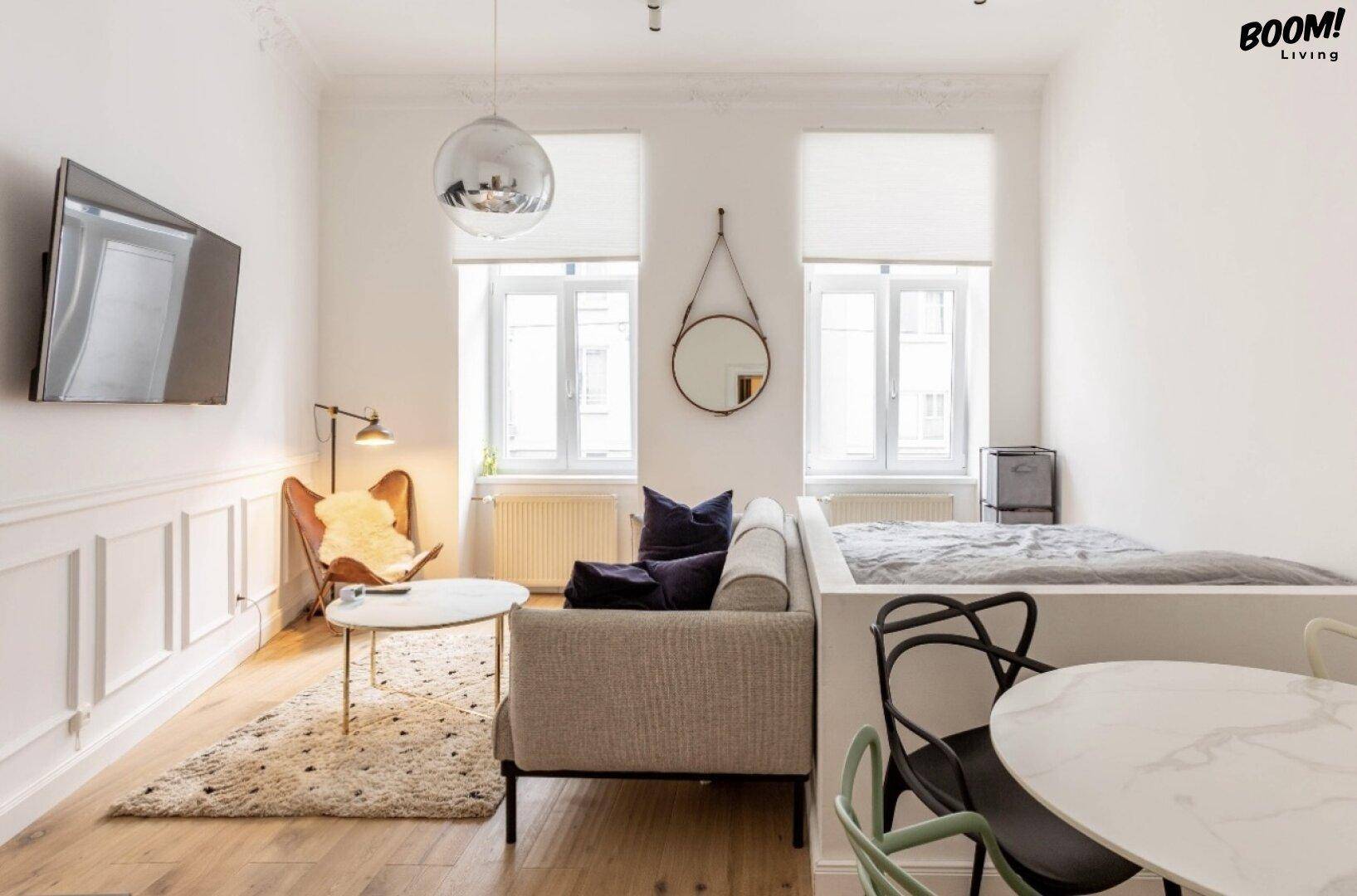 Helles Wohnzimmer mit Parkettboden, weißer Wandverkleidung und einem gemütlichen Sofa.