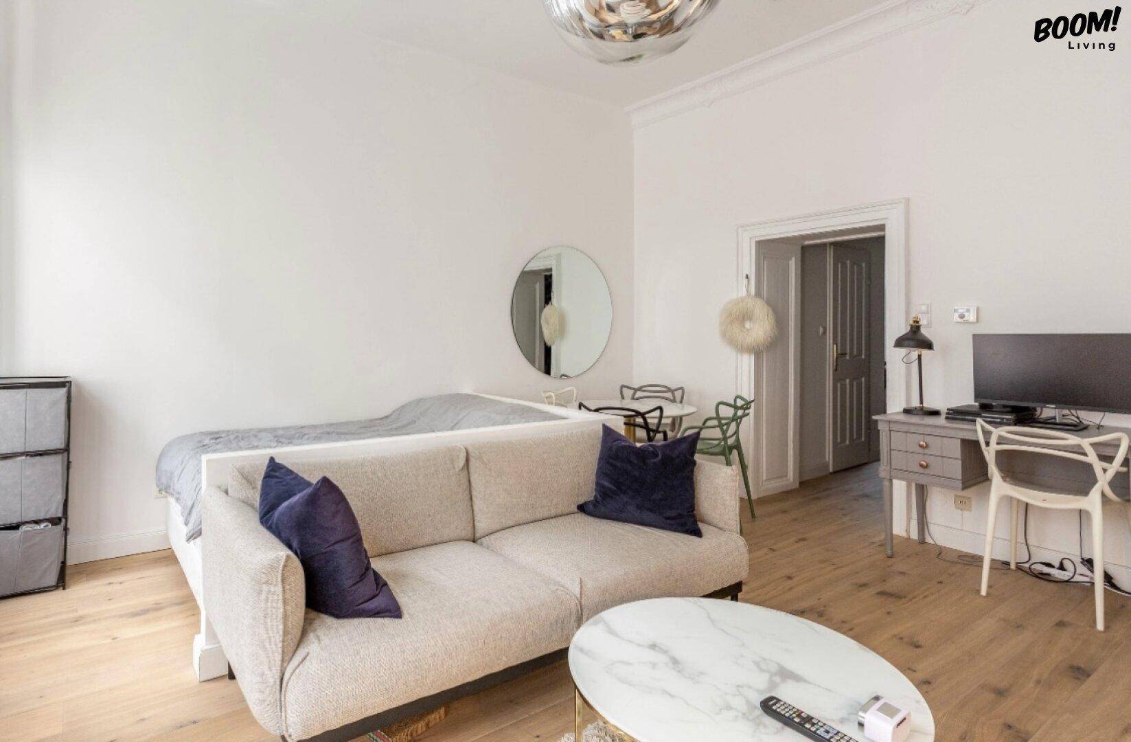 Geräumiger Wohnbereich eines Studios mit Schlafbereich, Sofa und Arbeitsplatz.