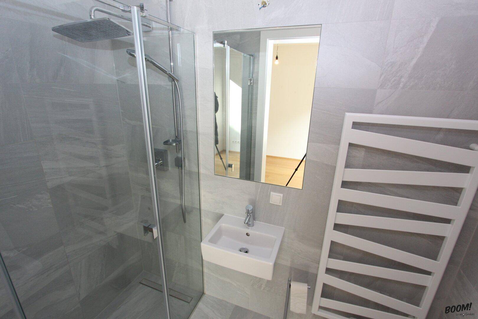Modernes Badezimmer mit ebenerdiger Dusche, Einzelwaschbecken und beheiztem Handtuchhalter.