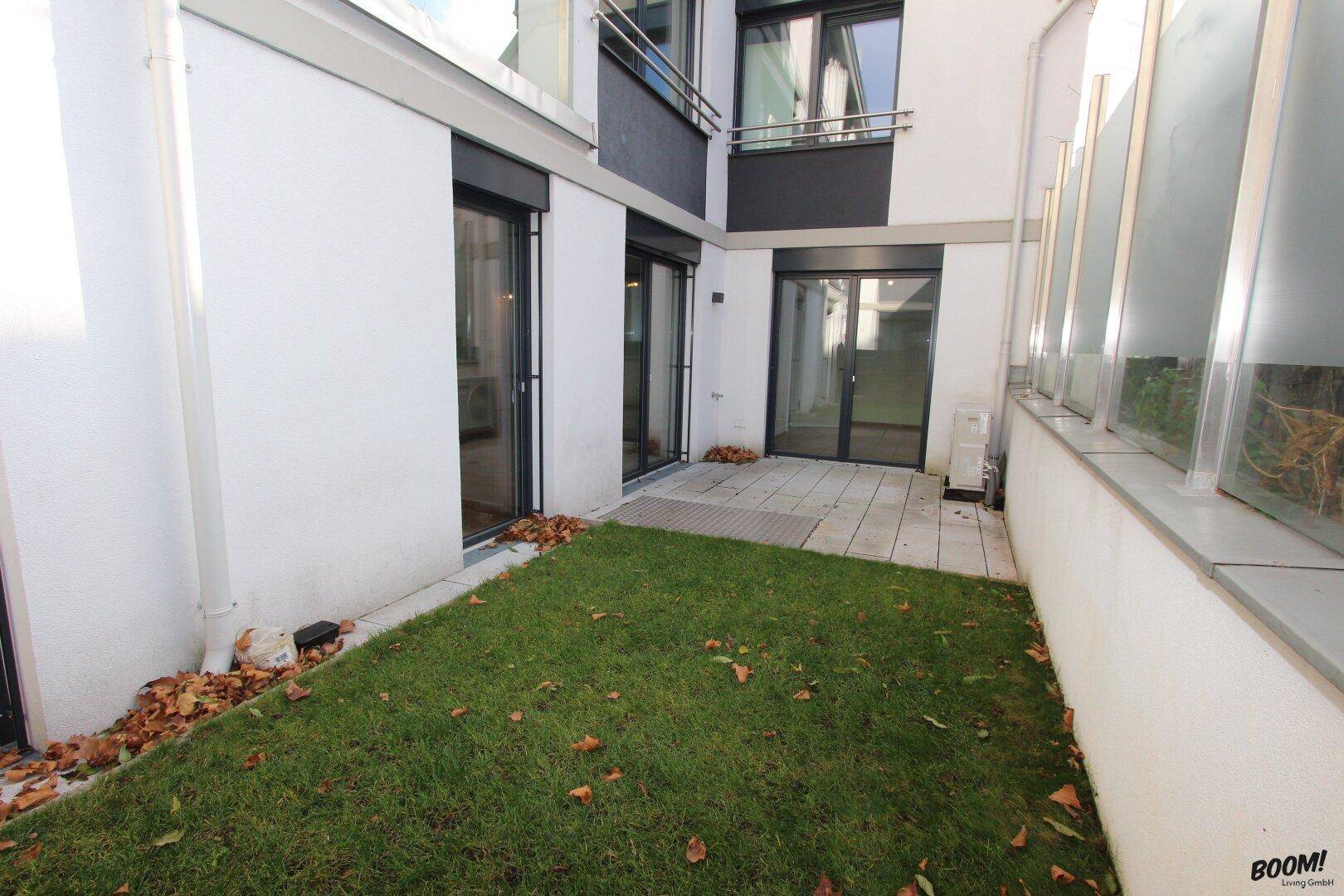 Kleiner privater Gartenbereich mit Rasenfläche und gepflasterter Terrasse.