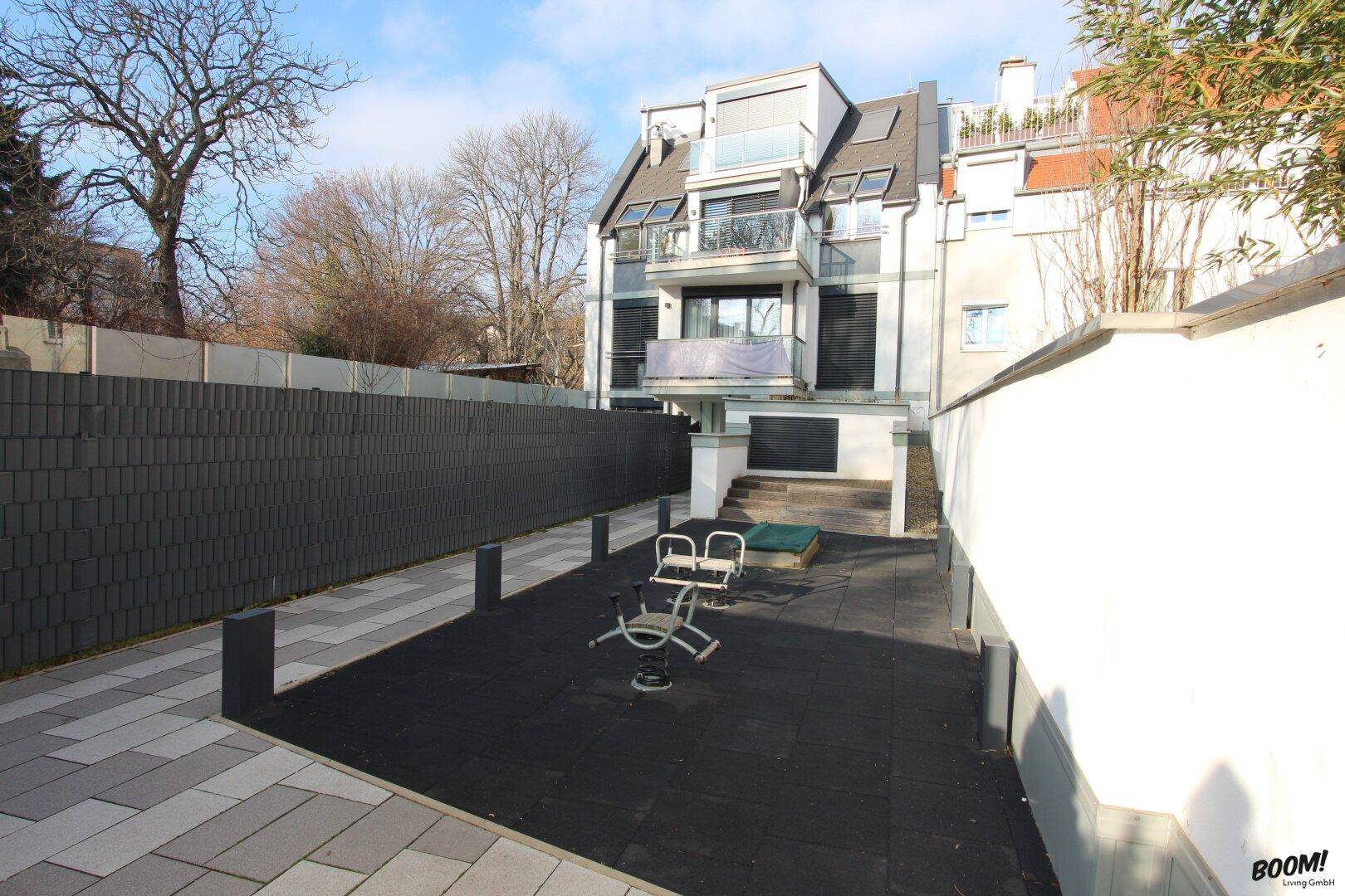 Außenbereich mit Kinderspielplatz und modernen Wohngebäuden im Hintergrund.