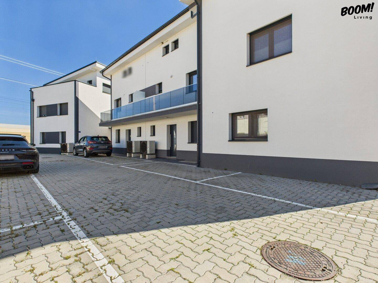 Modernes Mehrfamilienhaus mit Parkplätzen im Freien und Balkonen.