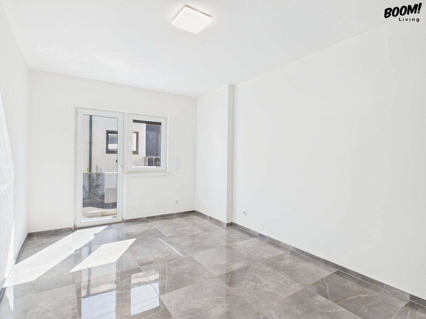 Helles Zimmer mit Fliesenboden und Zugang zu einem Außenbereich, ideal als Schlaf- oder Arbeitszimmer.