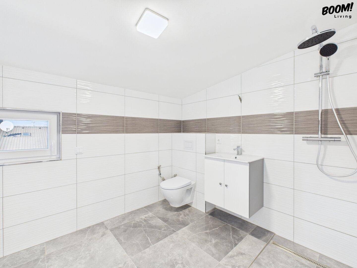 Modernes Badezimmer mit Dusche, WC, Einzelwaschbecken und Fenster.