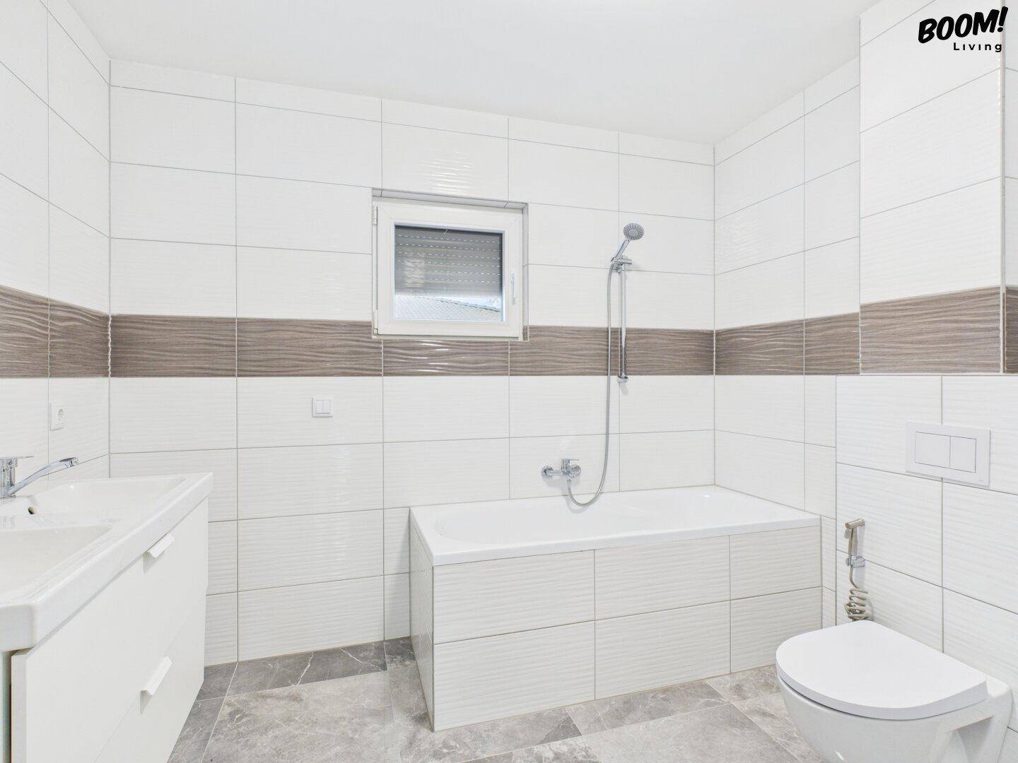 Modernes Badezimmer mit Badewanne, WC, Einzelwaschbecken und Fenster.