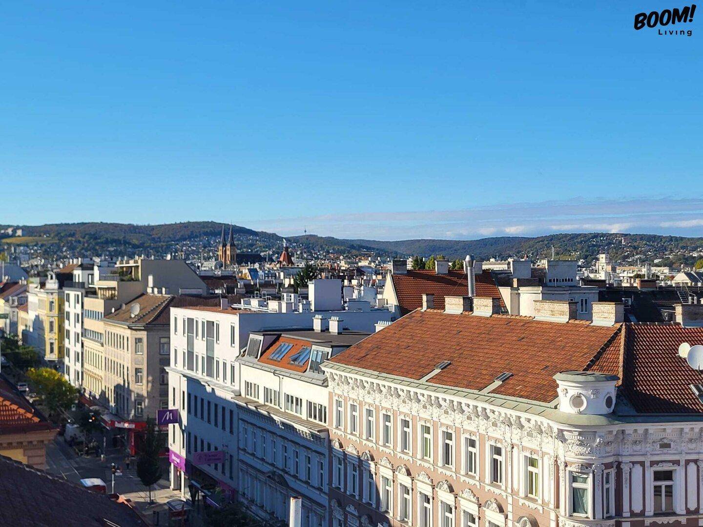 Panoramablick über eine Stadt mit historischen Gebäuden und hügeliger Landschaft im Hintergrund.