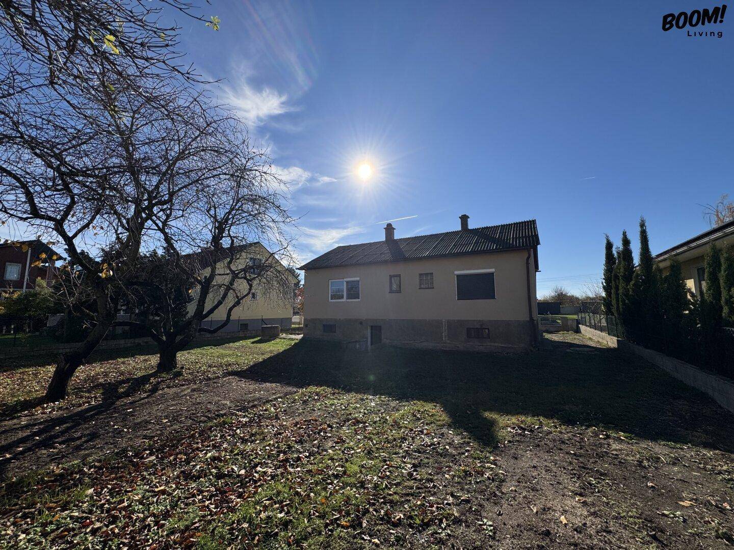 Rückansicht des Hauses vom Garten aus, mit Sonnenschein und umliegender Natur.