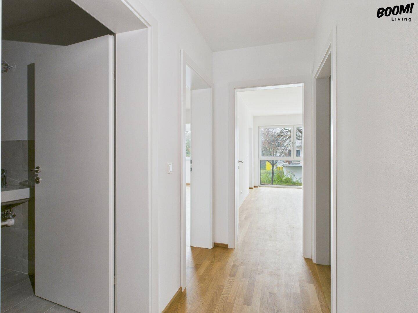 Langer, heller Flur mit Parkettboden, der verschiedene Zimmer der Wohnung verbindet.