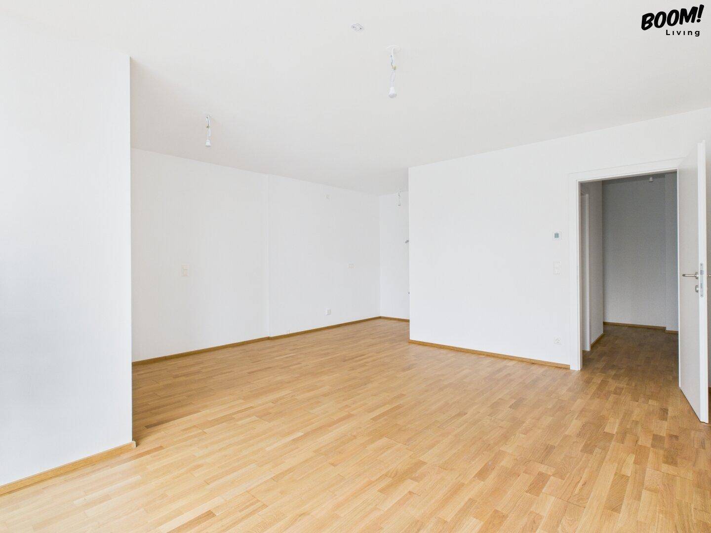Heller, leerer Raum mit Holzboden und weißen Wänden, vielseitig nutzbar.