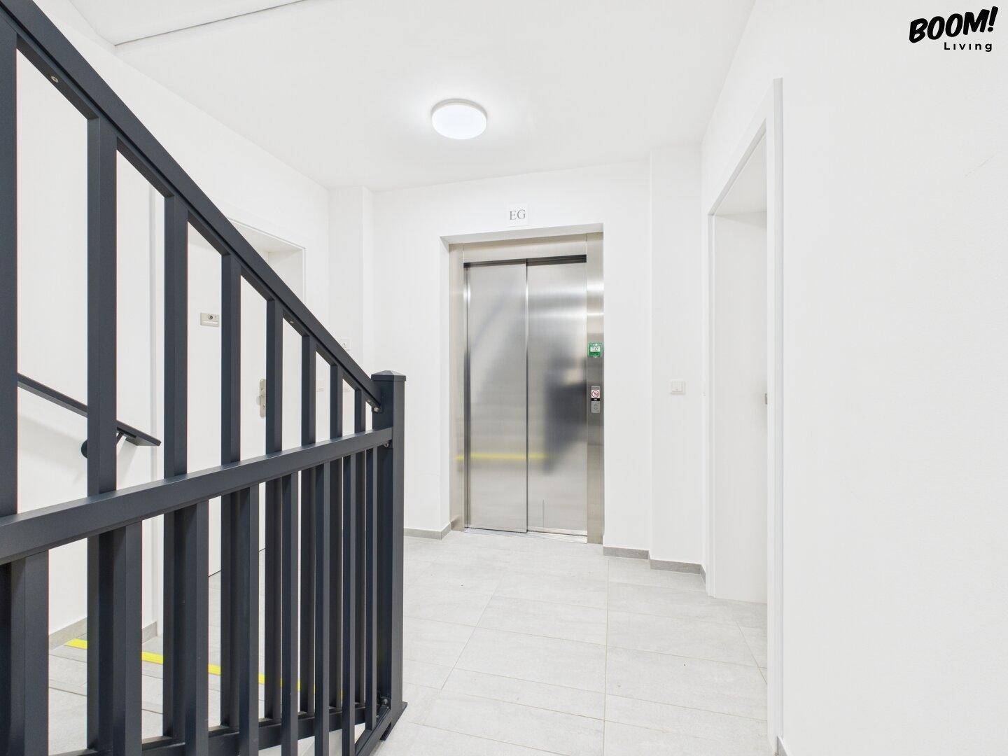 Heller Treppenhausbereich mit Aufzug und modernem Geländer in einem Mehrfamilienhaus.