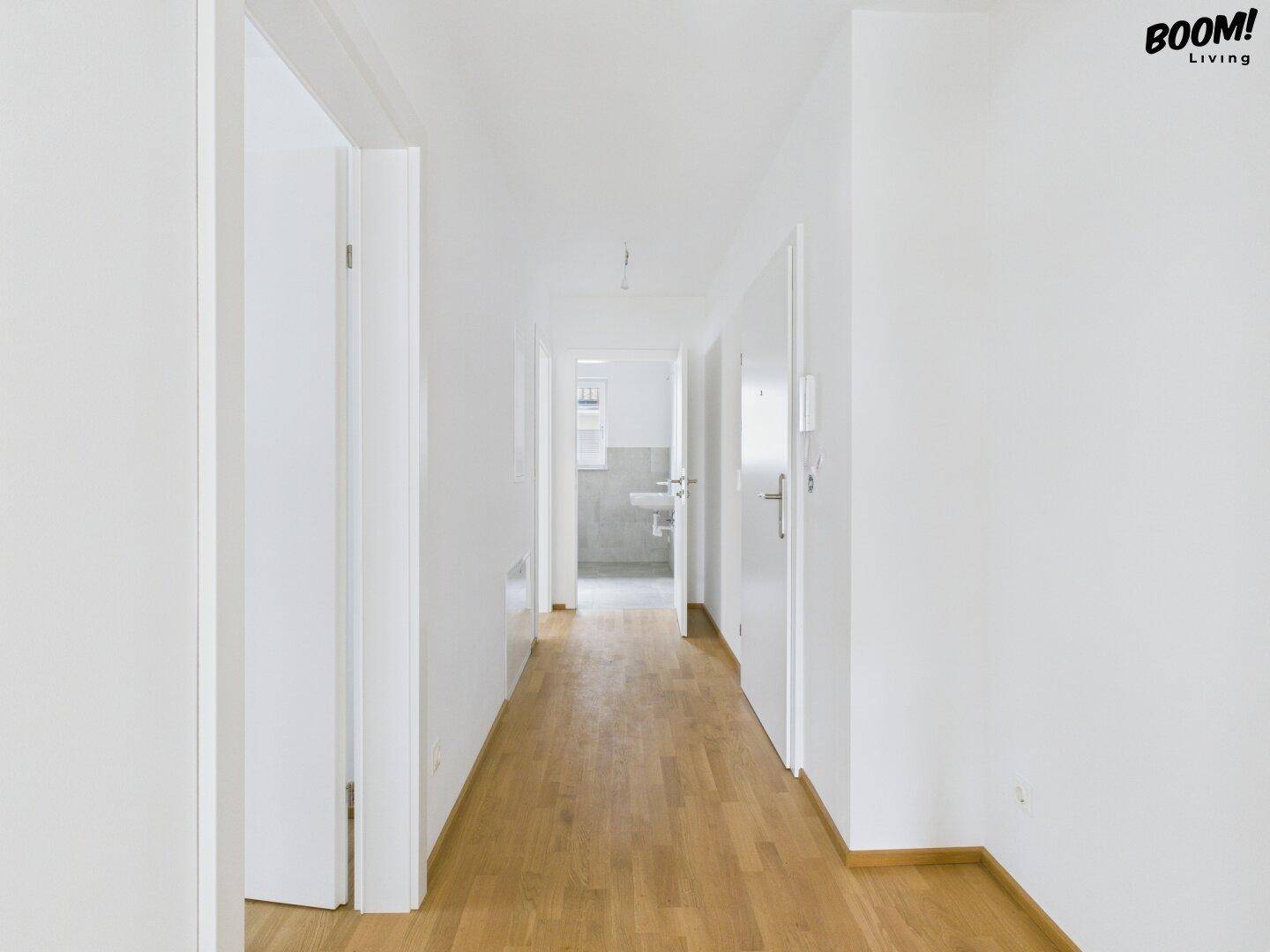 Heller Flur mit Holzboden, der zu weiteren Räumen und einem Badezimmer führt.