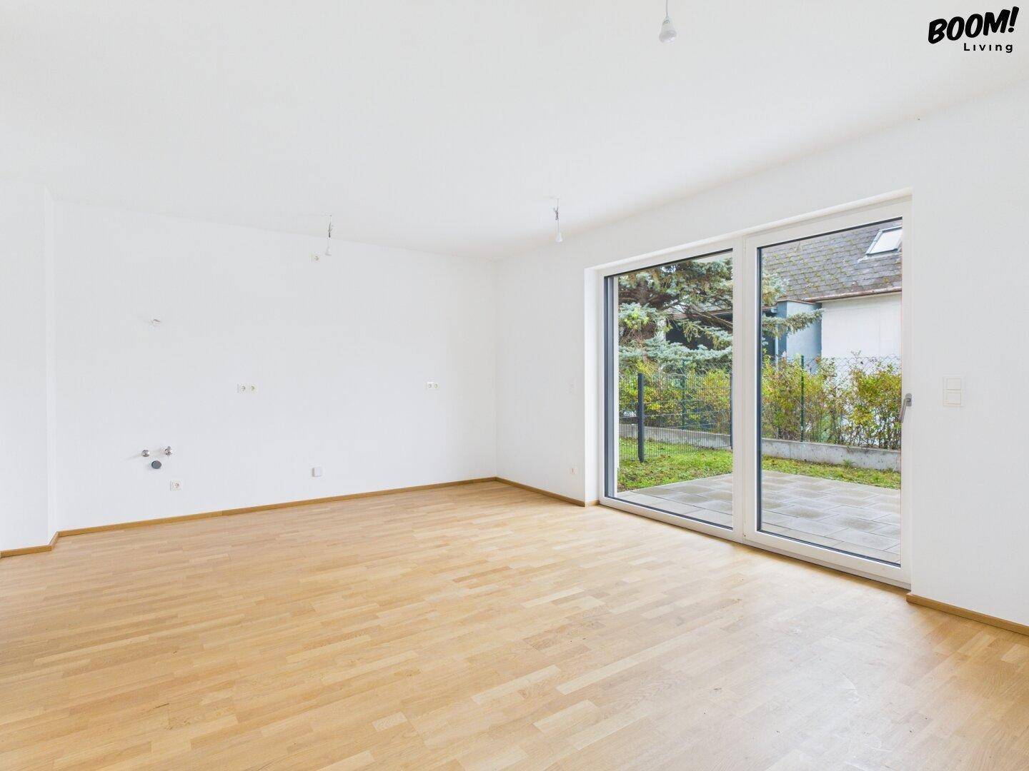 Geräumiger, heller Raum mit Holzboden und großen Schiebetüren zur Terrasse.