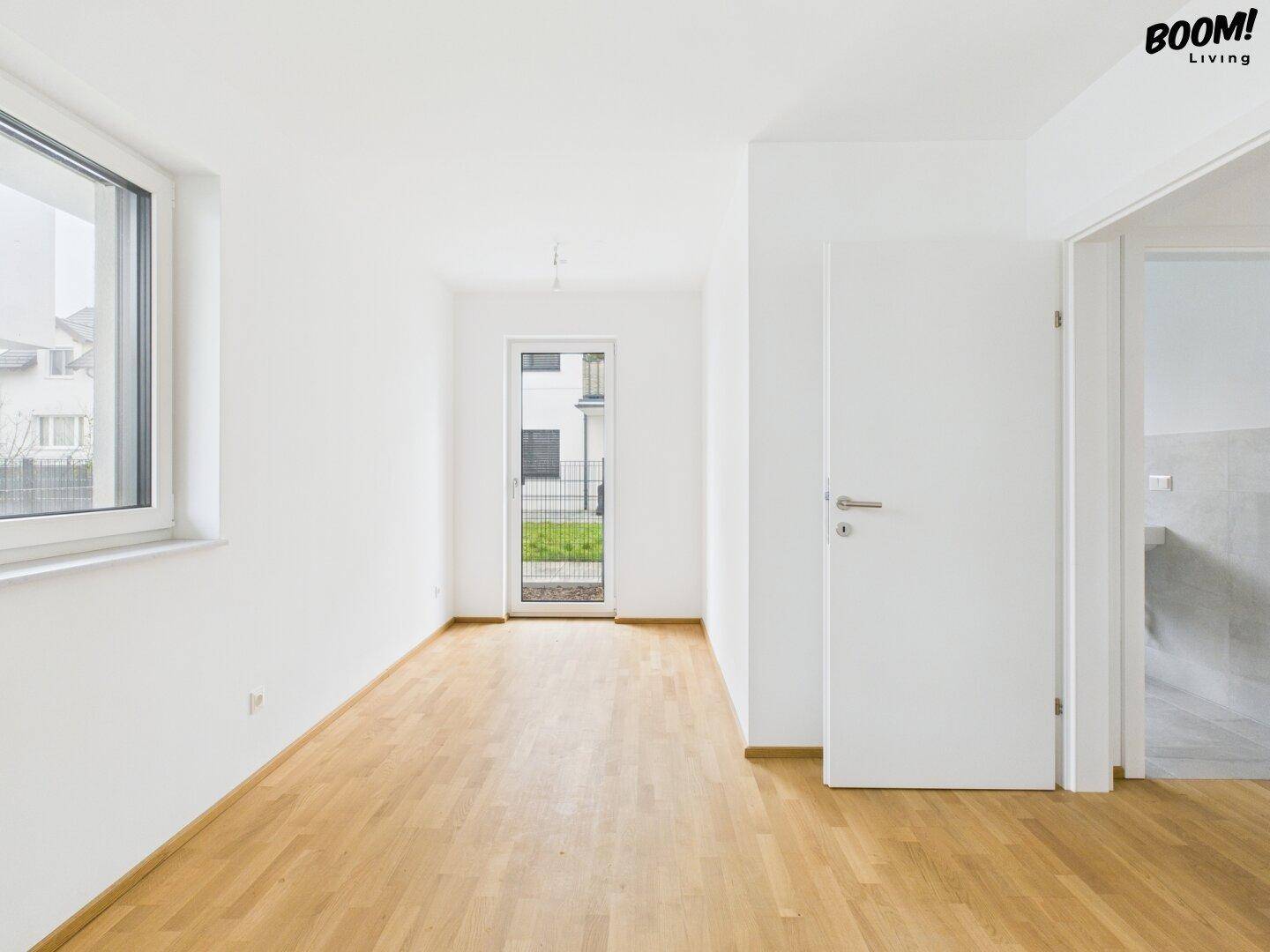 Heller Raum mit Holzboden und Zugang zum Außenbereich, vielseitig nutzbar.